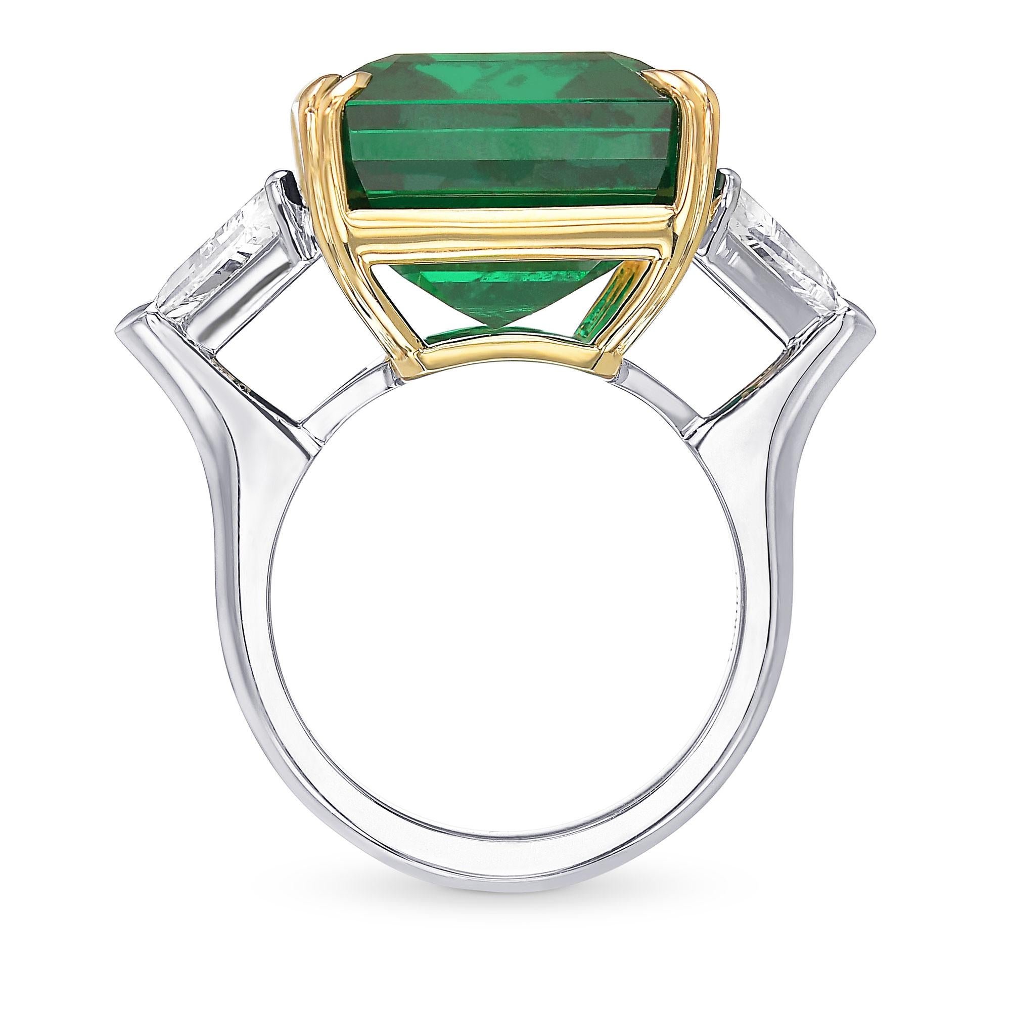 Uno splendido anello a tre pietre con smeraldo verde vivo e diamante, con una gemma centrale del peso di 20,78 carati e certificato da CD. La pietra è affiancata da una coppia di diamanti triangolari incolori e tutte e tre le pietre sono incastonate