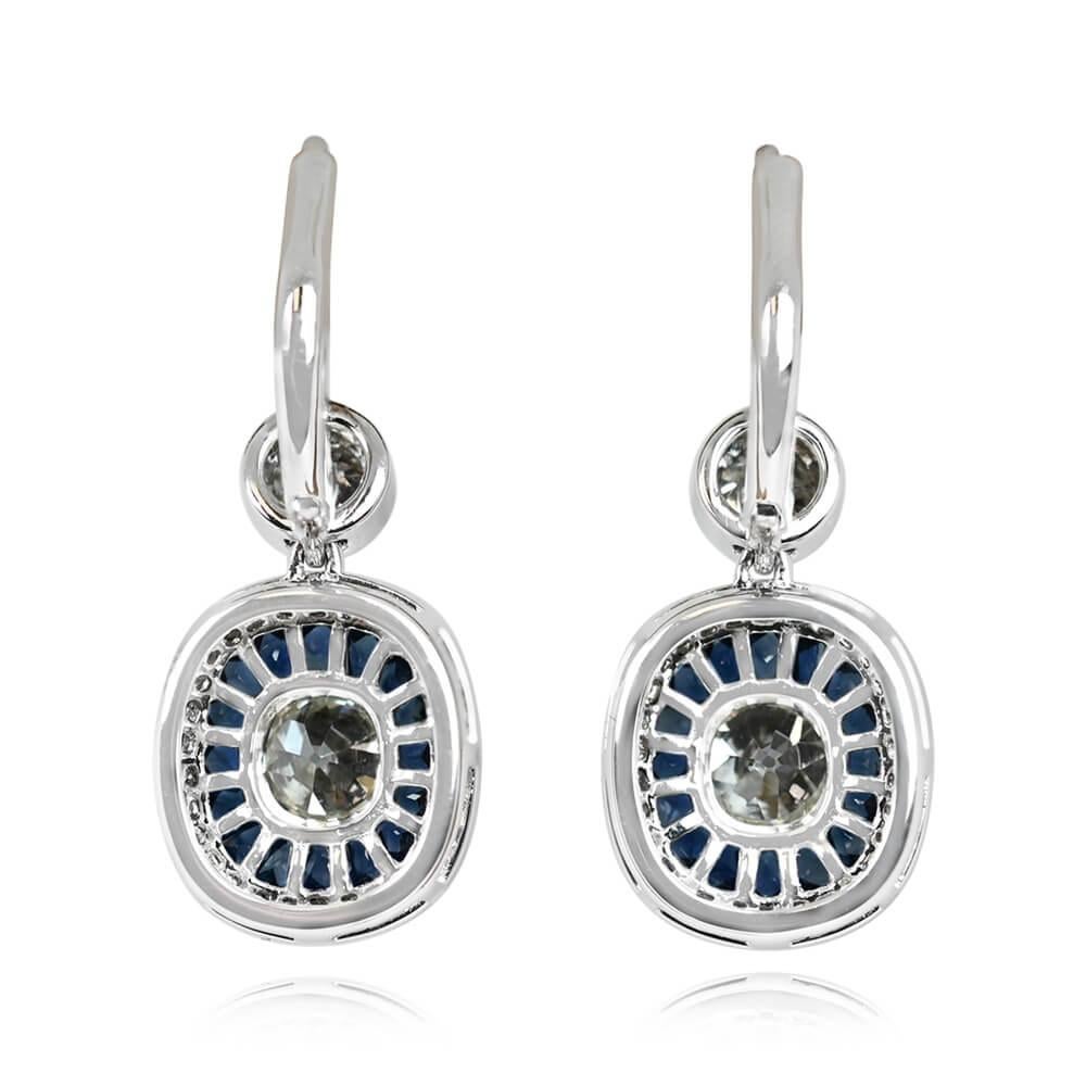 Experience enchantment with this stunning pair of diamond and sapphire earrings. Each features bezel-set antique cushion cut center diamonds, weighing around 0.50 carats each. These are embraced by a double halo of French cut sapphires and round