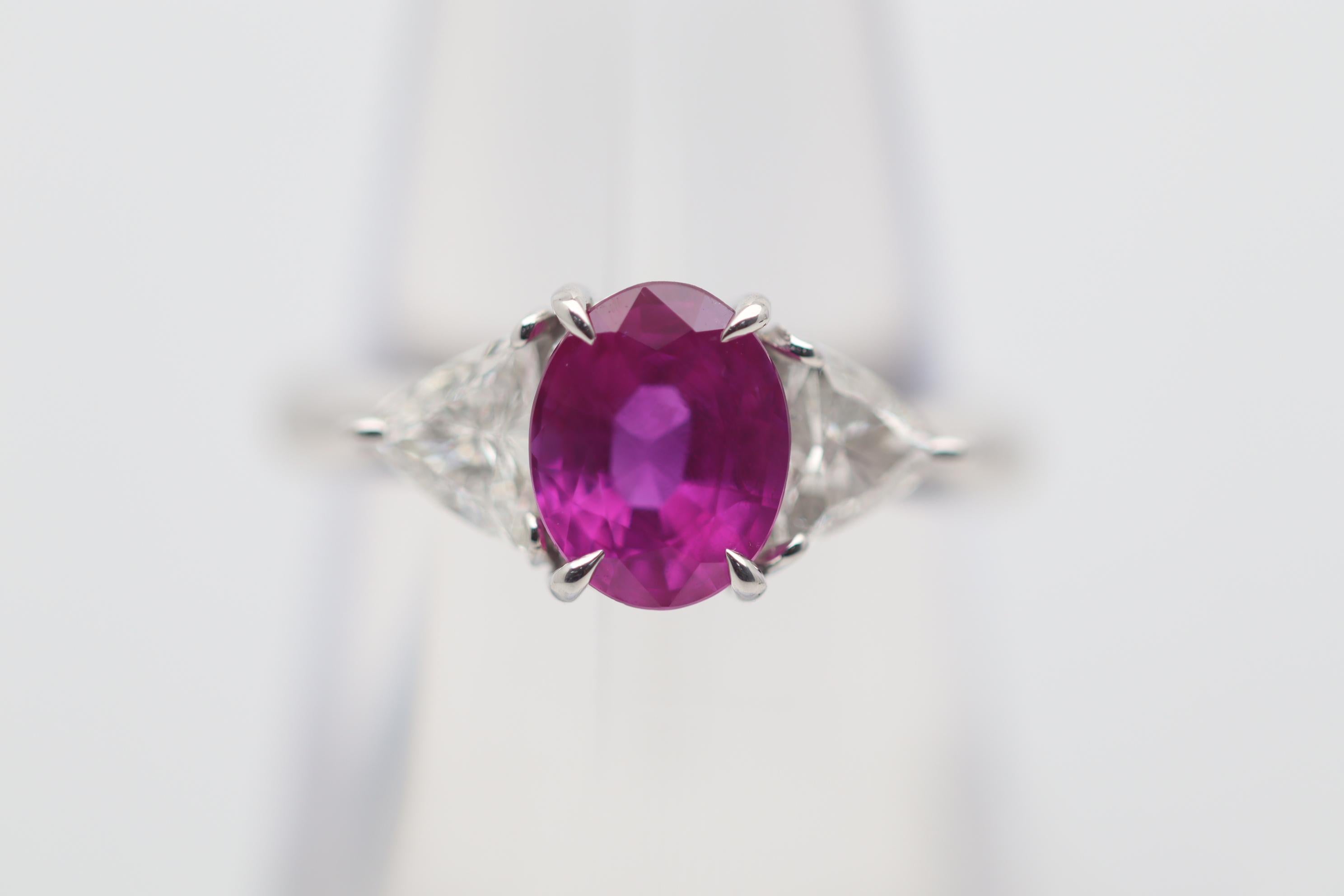 A classic stylish 3-stone gemstone platinum ring featuring a fine vivid pink sapphire! The sapphire weighs 2.08 carats and has a rich intense vivid pink color making it almost like a ruby! It is complemented by 2 triangular-cut diamonds set on its
