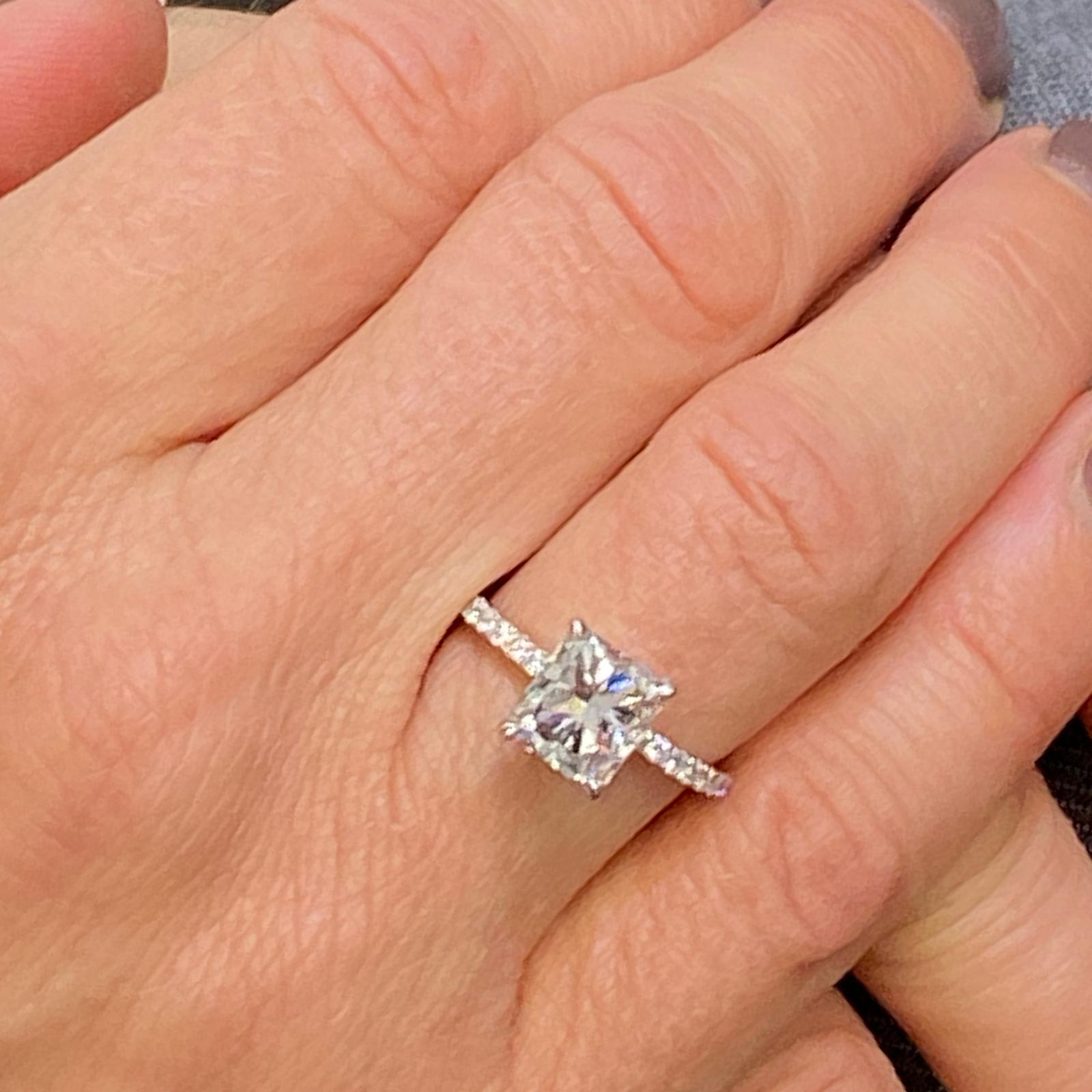 Radiant Diamond Engagement Ring fashioned in 18 karat white gold. The 2.08 carat radiant diamond is graded E color and VS1 clarity by the GIA. The diamond is set in an elegant modern diamond band featuring 28 round brilliant cut diamonds weighing