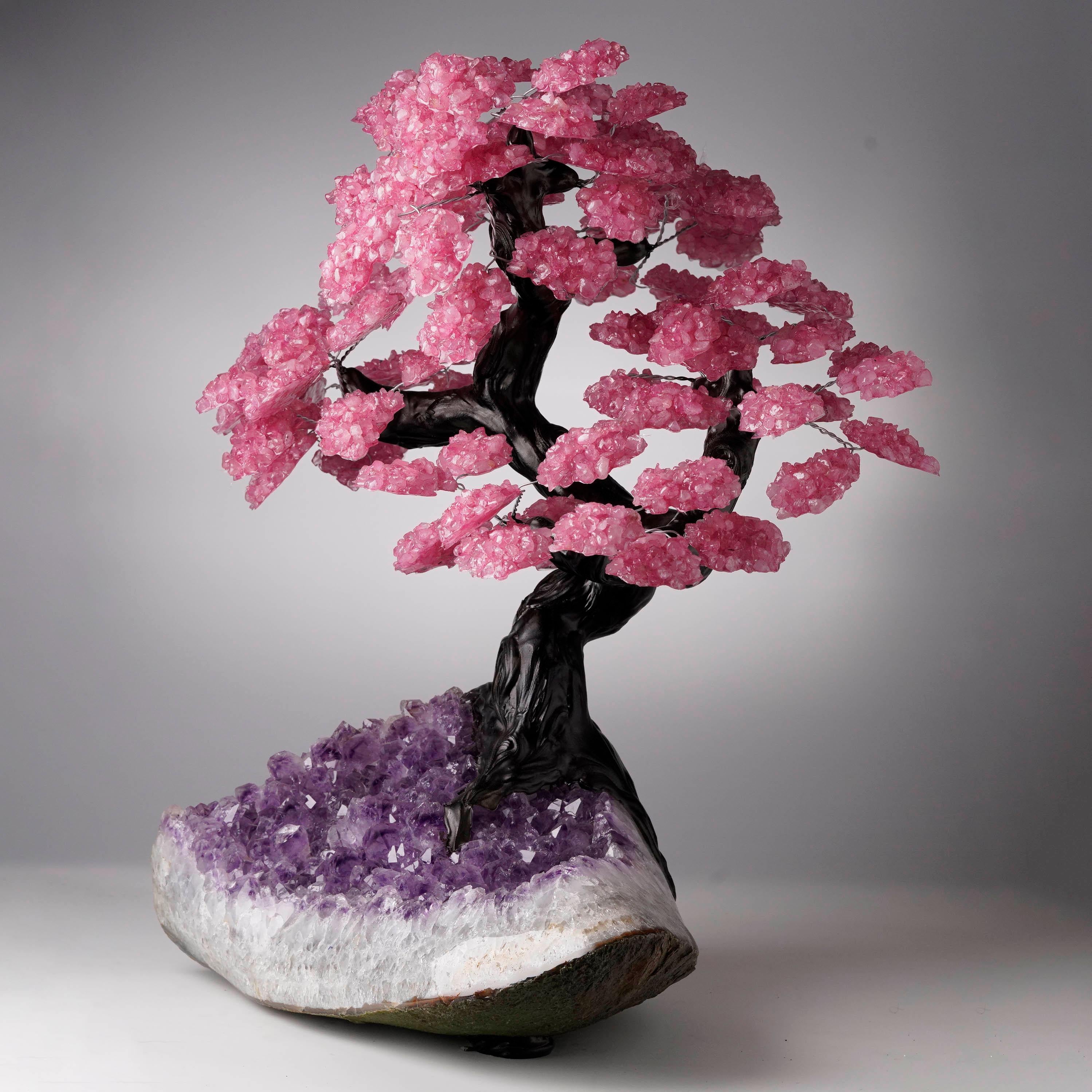 Cet arbre de cristal fabriqué à la main présente de délicates fleurs de quartz rose véritable, enracinées dans une grande grappe d'améthyste naturelle aux teintes vives. Le contraste et l'équilibre entre la forme et la couleur en font une pièce