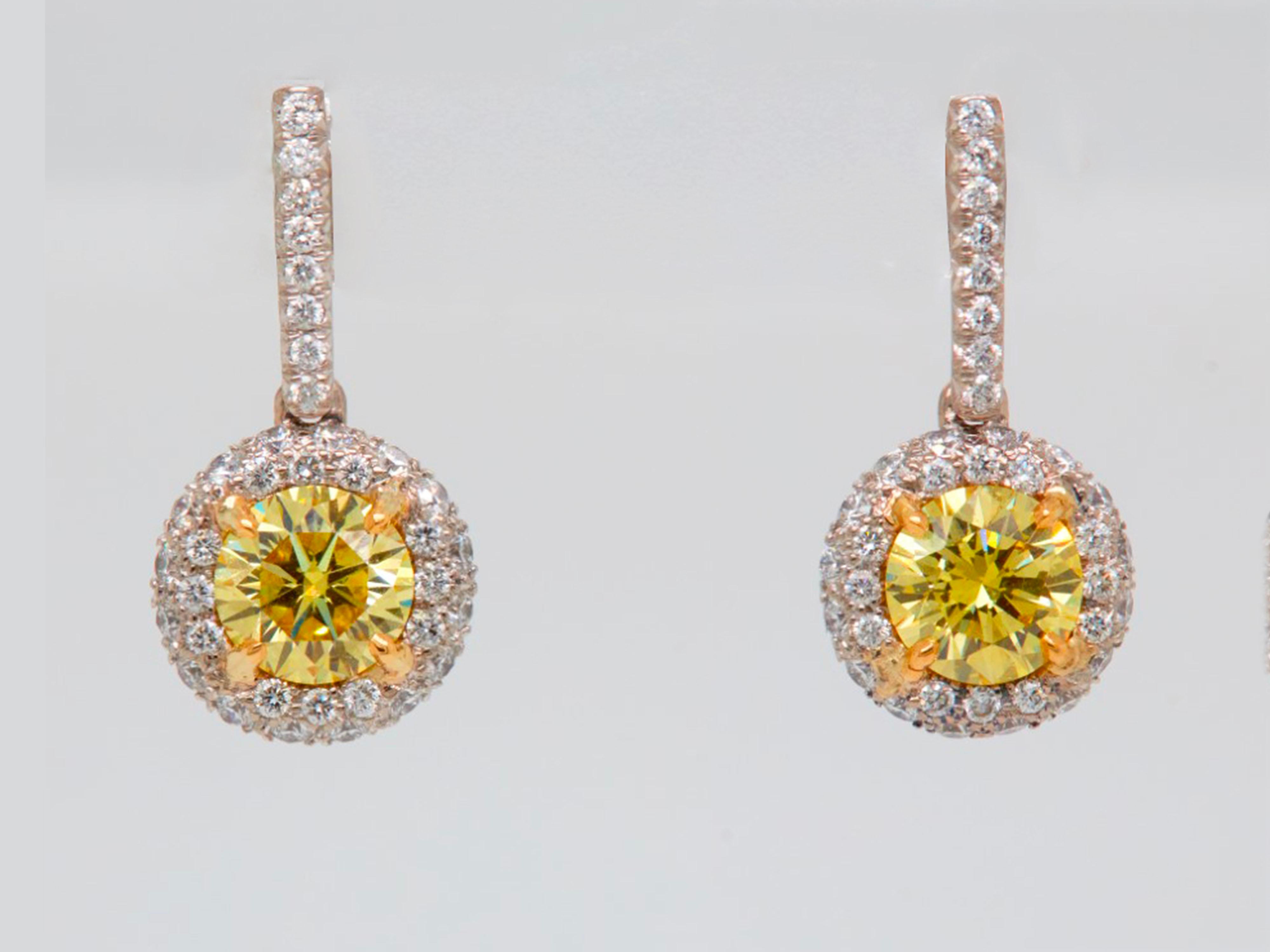Novel Collection showcasing a stunning pair of 2.09 carat round brilliant diamond with halo drop earrings, GIA certified as VS+ clarity and J color.
Set with a perfect match of Fancy Vivid Yellow round brilliant cut 1.04 carat, VS1 clarity, GIA