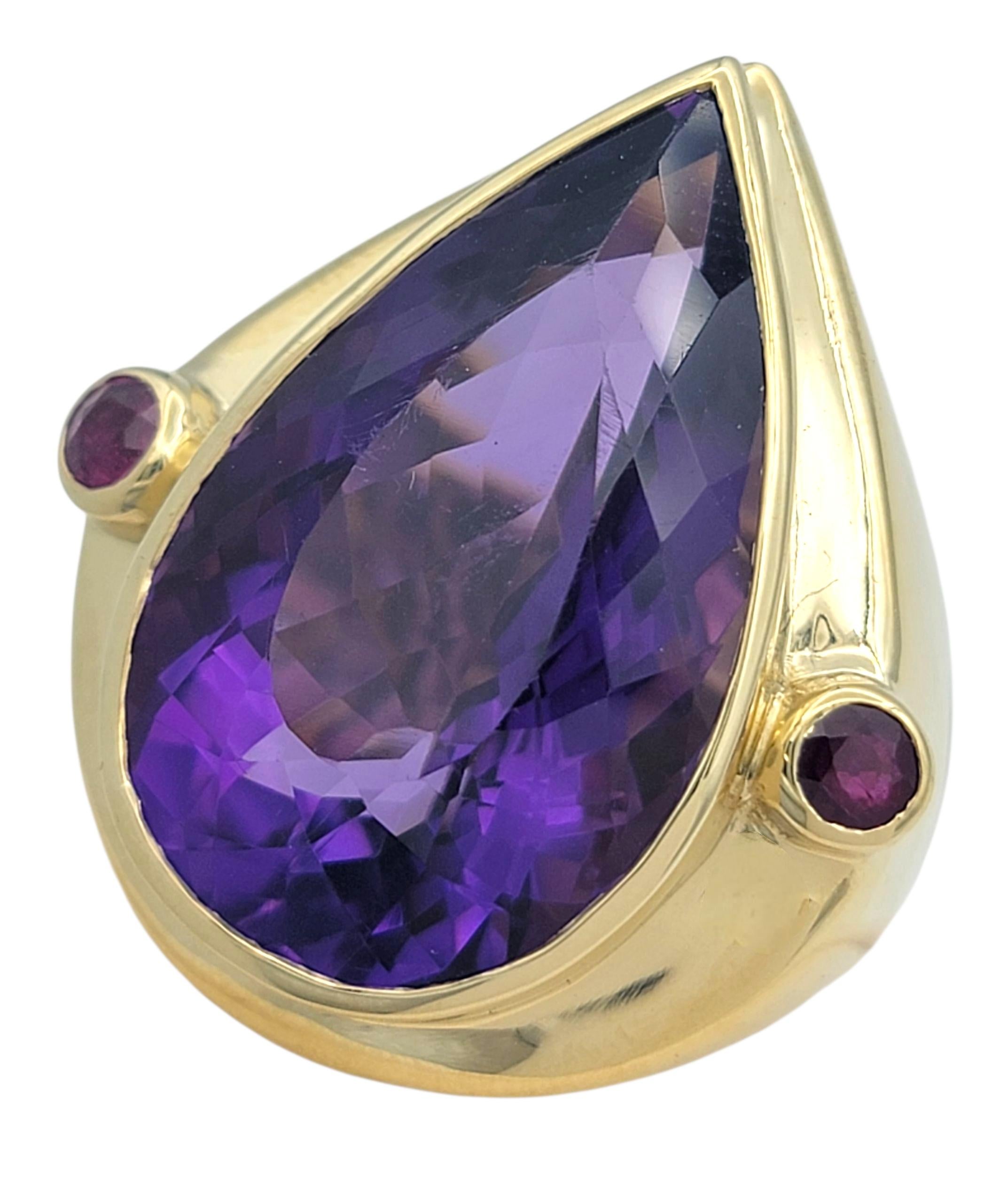 D'une taille imposante et d'une couleur captivante, cette bague exquise est centrée sur une lumineuse améthyste en forme de poire qui rayonne d'une riche et royale teinte pourpre. La taille et la clarté impressionnantes de la pierre précieuse
