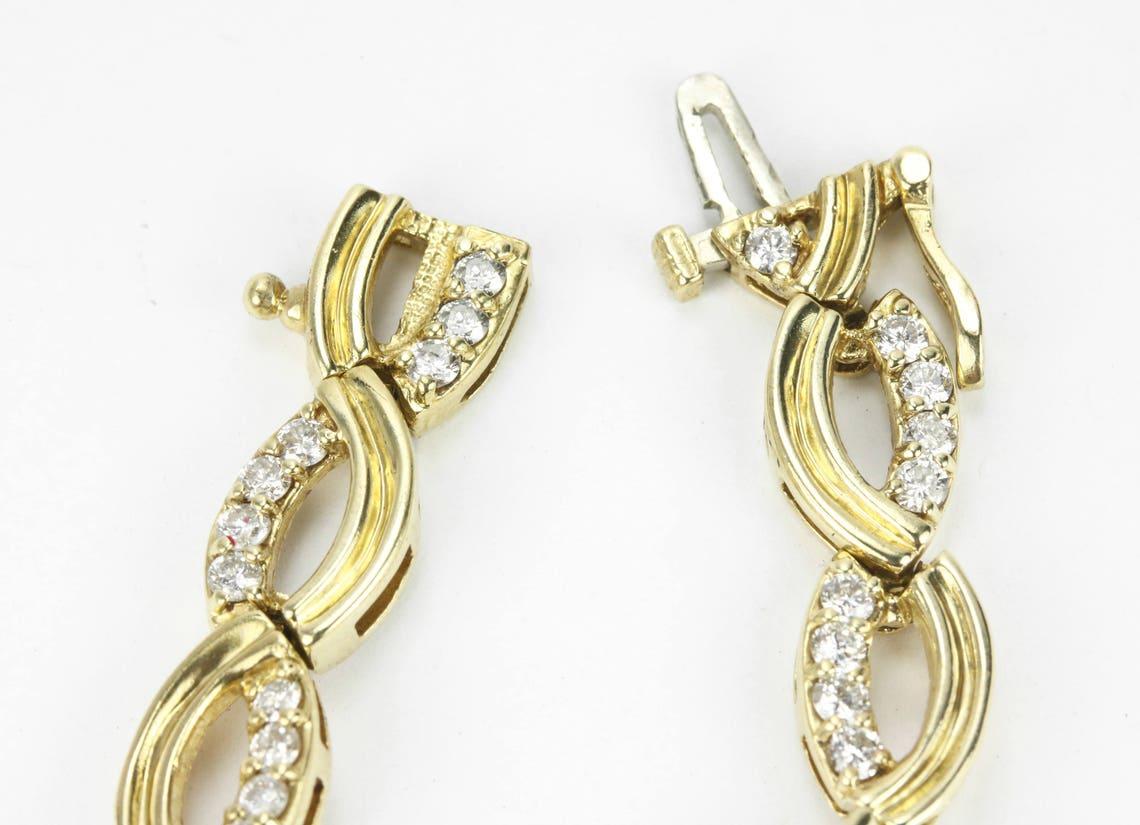 Una pulsera de diamantes de eslabones fantasía en oro amarillo de 14 quilates. Esta pulsera presenta un exclusivo eslabón dorado adornado con diamantes blancos. Los eslabones se asemejan a signos de infinito y están fabricados en elegante oro muy