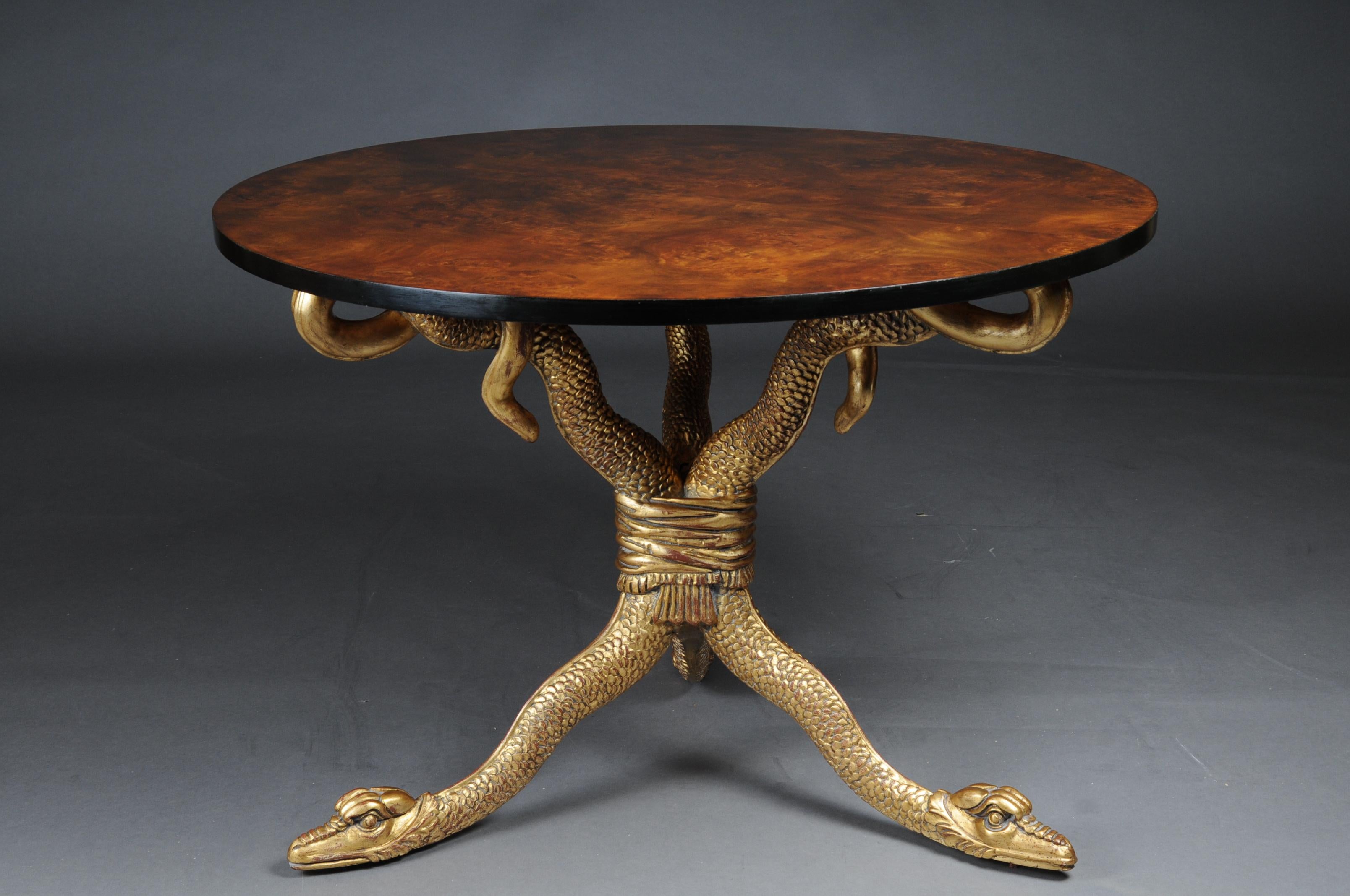 20th century snake table design after K. F. Schinkel Empire manner

Three fully plastic snakes carved from solid beech wood and gilded with poliment. The beatings are on a three-sided raised base plate. Maple root veneer partially ebonized on solid