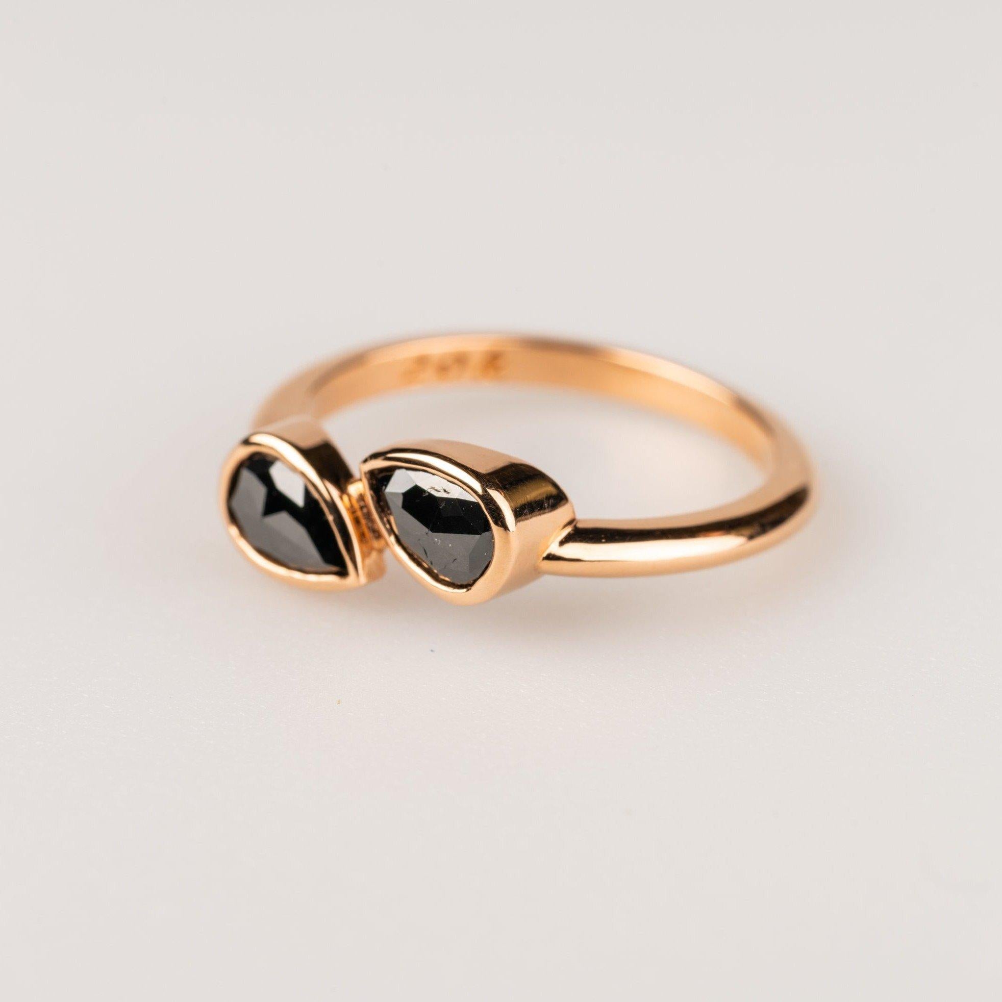 A 20k rose gold ring featuring two bezel set pear shaped rose cut black diamonds .6 total carats. Ring size 7. This ring was made and designed by Sydney Strong.