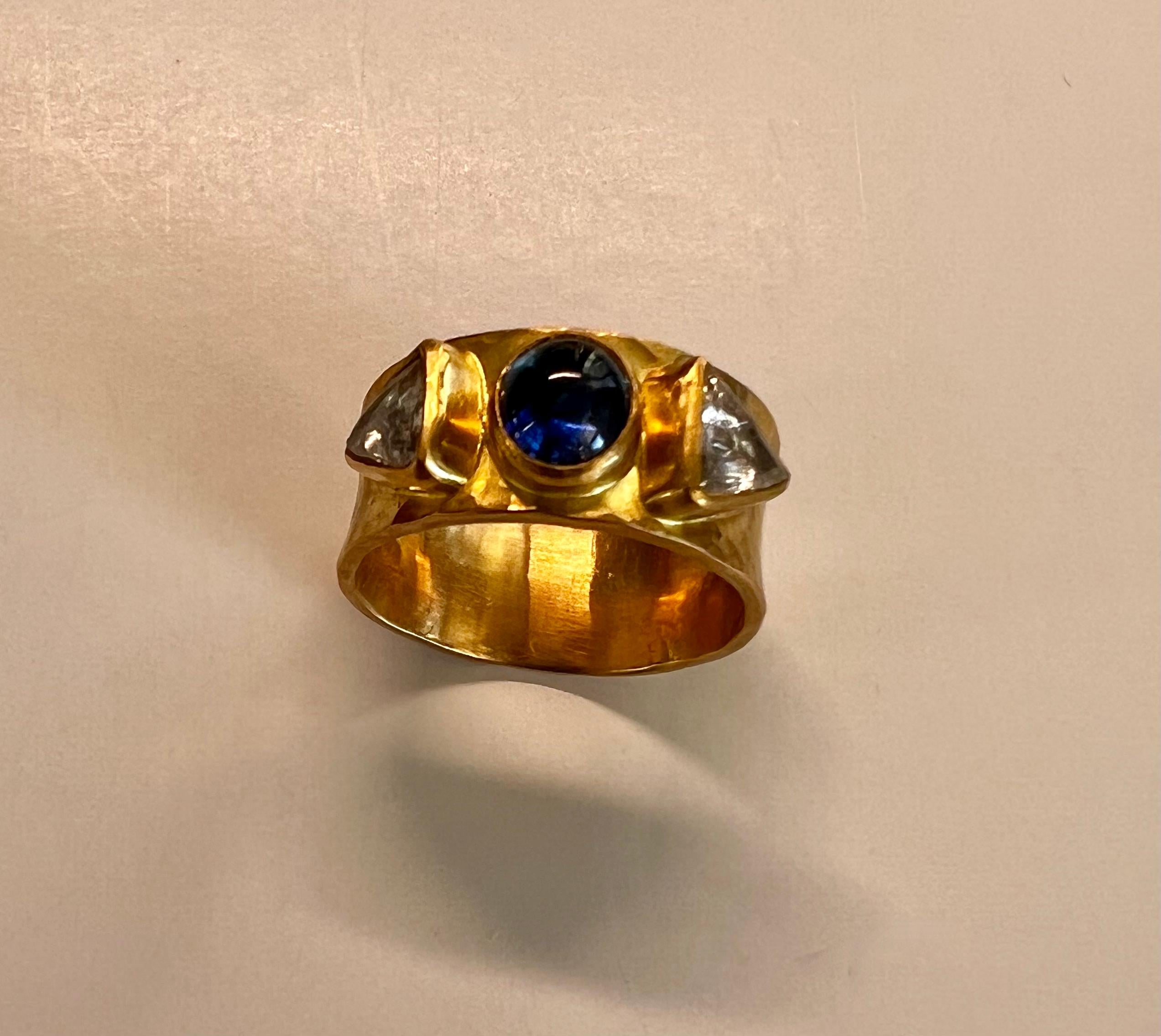 Ring aus 20 und 22 Karat mit ovalem blauem Saphir-Cabochon und Macle-Diamanten, eingefasst in ein gehämmertes Band.
Ein Macle ist eine kristalline Form, ein Zwillingskristall oder ein Doppelkristall, wie er in oktaedrischen (8) Kristallen oder