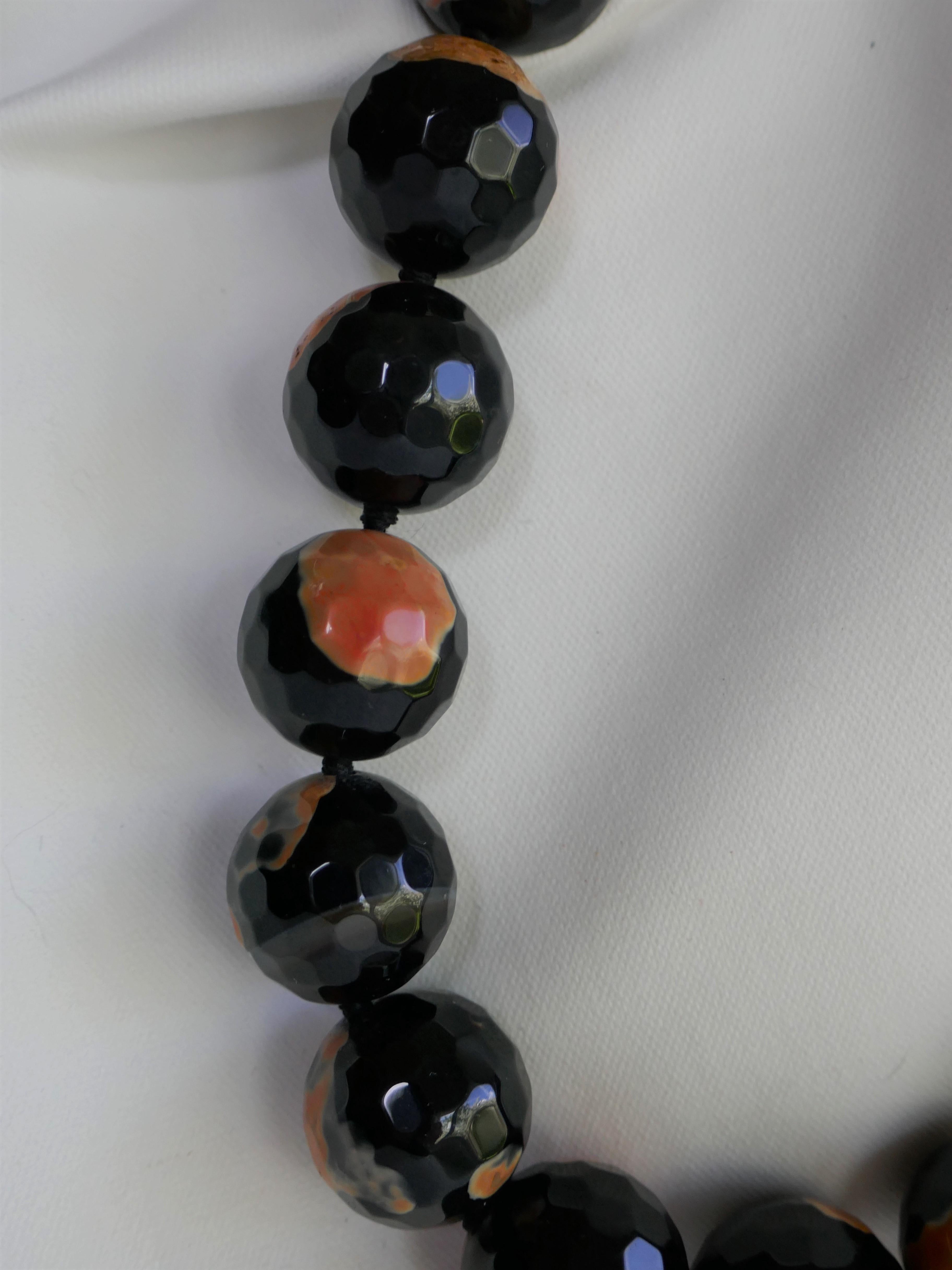 This 20mm beads faceted fire agate necklace is classic,  modern and makes a statement.  This particular fire agate has orange coral hues bead throughout the bead. The necklace looks amazing on.  It is individually knotted with black silk thread. The