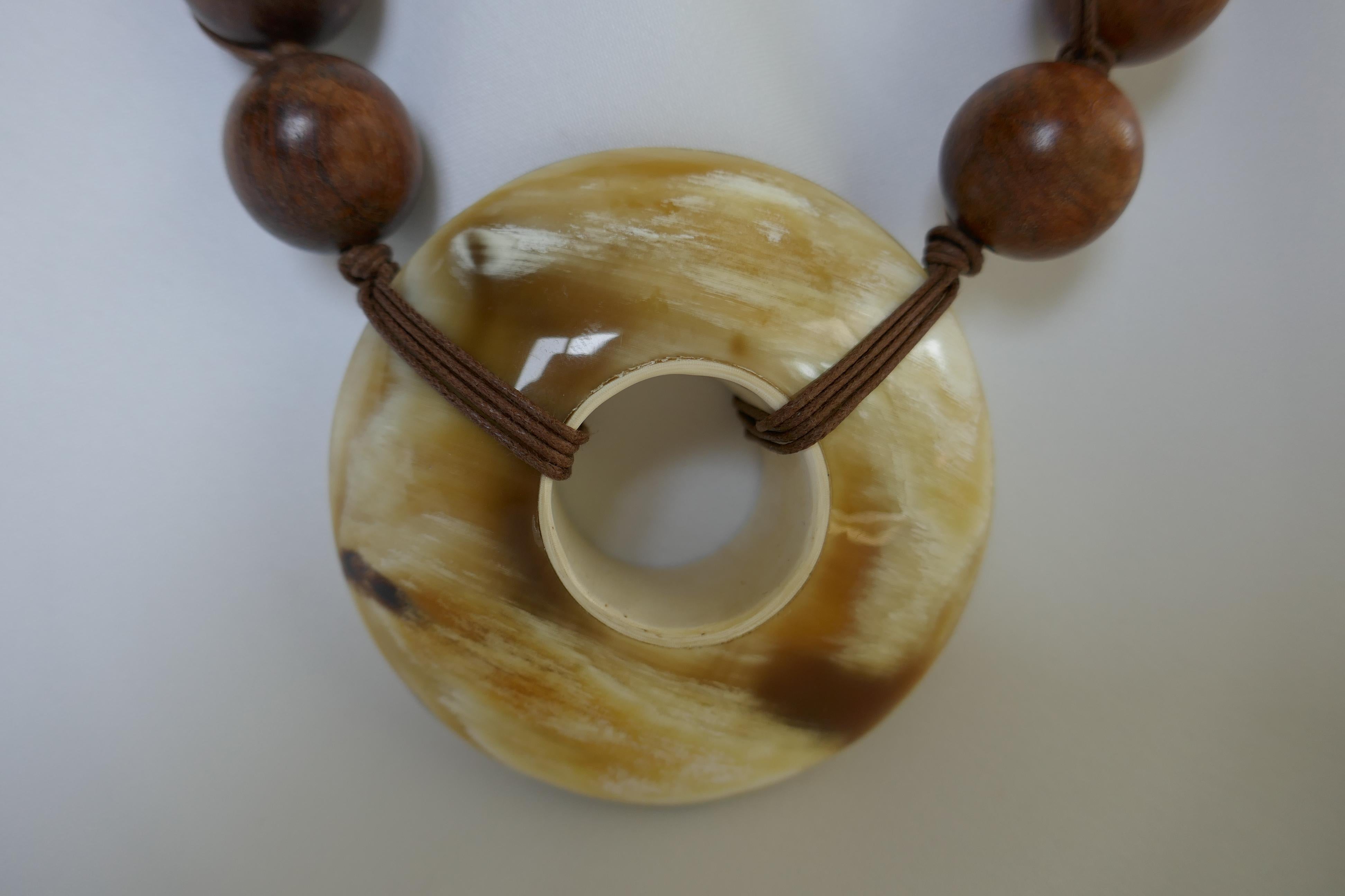 The necklace is 20 mm beads with a large horn doughnut. The necklace is individually knotted on cotton cord and the cord is also  wrapped on the outside of  each wood bead. A statement necklace. The horn doughnut is 72mm. The closures is wood and