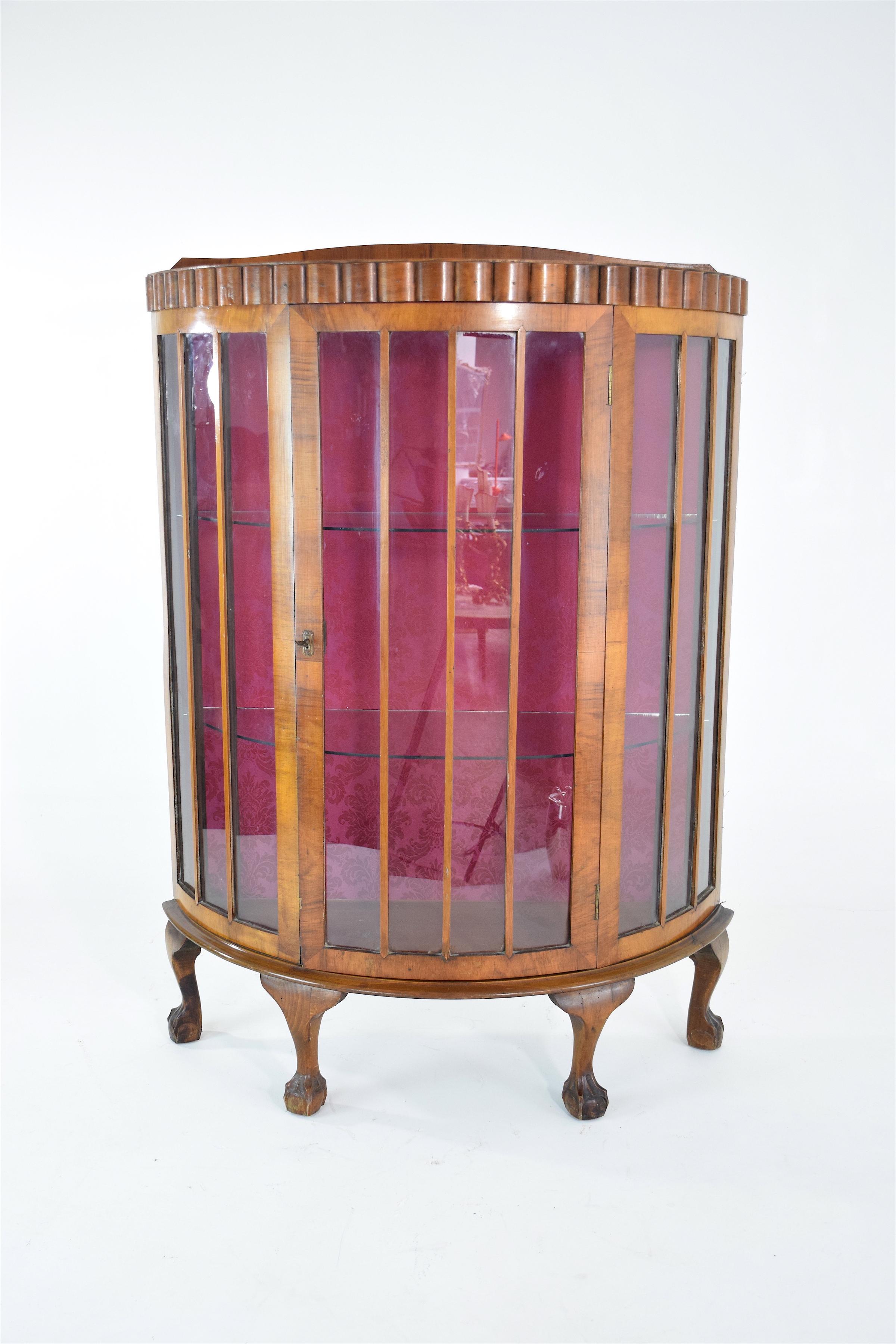 A French 20th-century vintage demi-lune vitrine or display cabinet composed of oak and sitting on four cabriole legs. The interior is adorned with a vibrant pink flower motif upholstery. This storage piece opens with the center glass keyed door