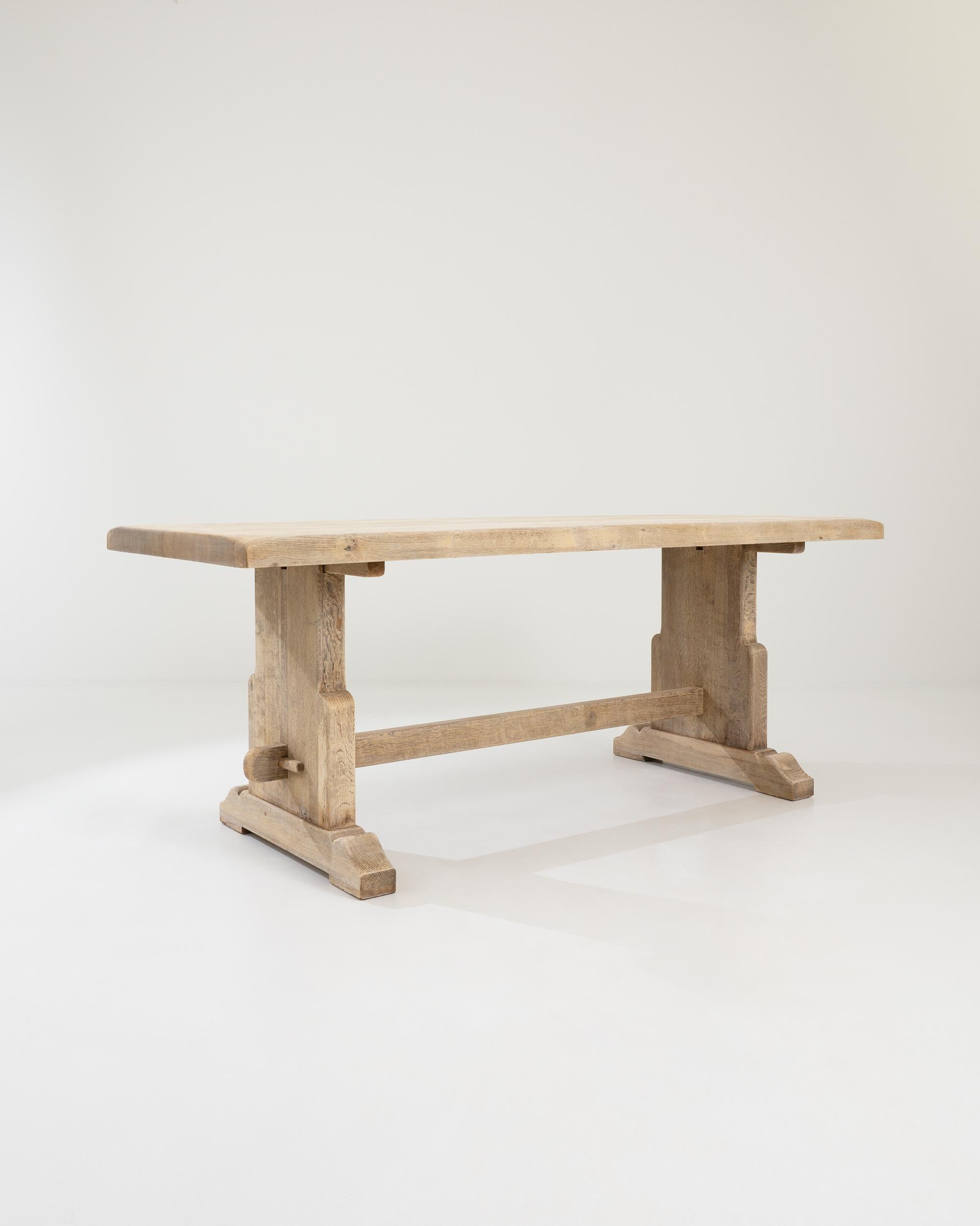 A wooden dining table created in 20th century Belgium. Characteristic of traditional Belgian design, this table is sturdily constructed and contains a forthright air of purpose and utilitarian function. Thick slabs of oak, thoughtfully joined