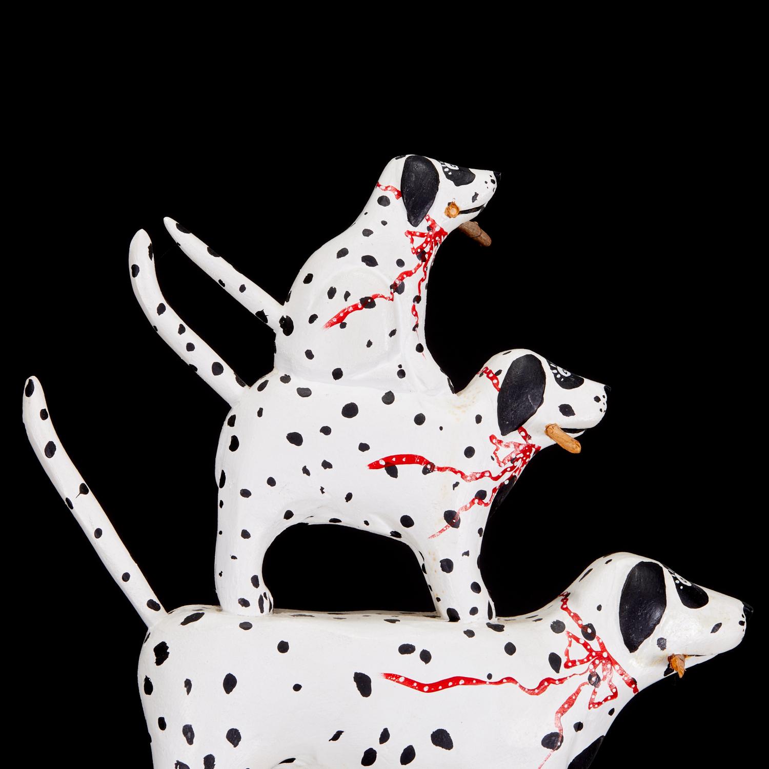 c. 1988, Bruce Murphy (American) a carved and painted wood sculpture of five dalmations of graduated sizes standing on each other's backs, signed on seated dog's paw. Each dog sports a red ribbon with white polka dots and is holding a stick in their