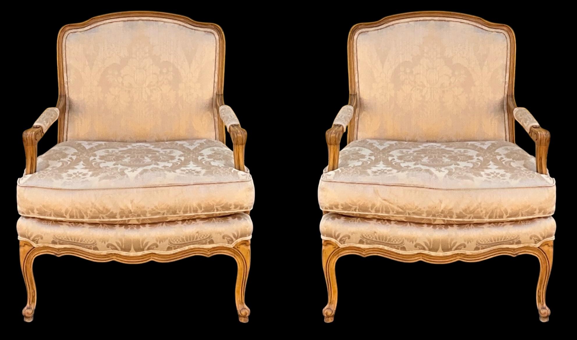 Il s'agit d'une paire de chaises bergères de style Louis XV, recouvertes d'une tapisserie d'époque en damas. Les cadres sculptés sont en hêtre. Les coussins sont enlevés. Il y a également un coussin de dossier libre au-dessus des dossiers