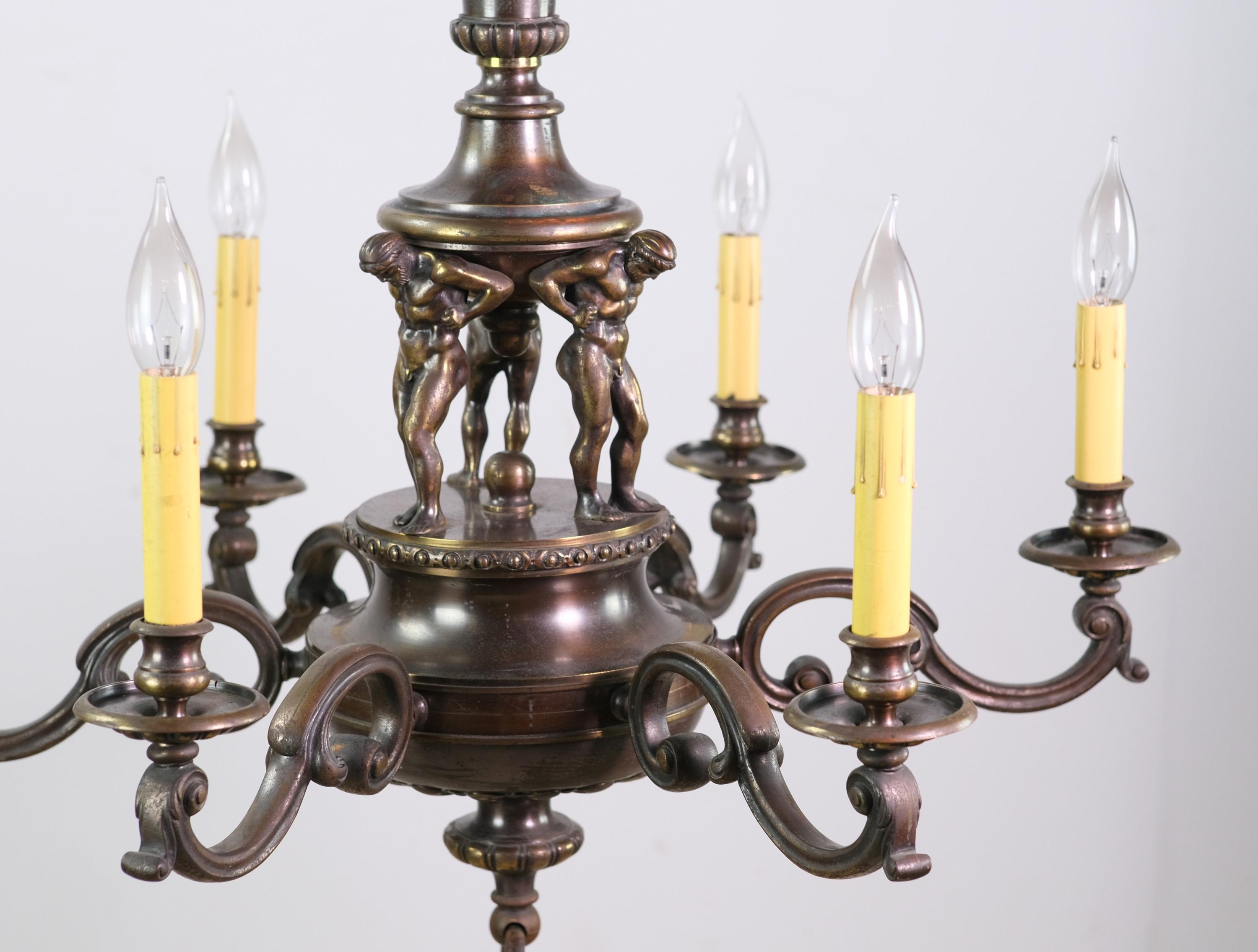 Early 20th century highly detailed bronze French Empire bronze chandelier. Features three male Atlas figures holding up the upper hub of the chandelier resting on their backs. Comes with the original ceiling canopy.