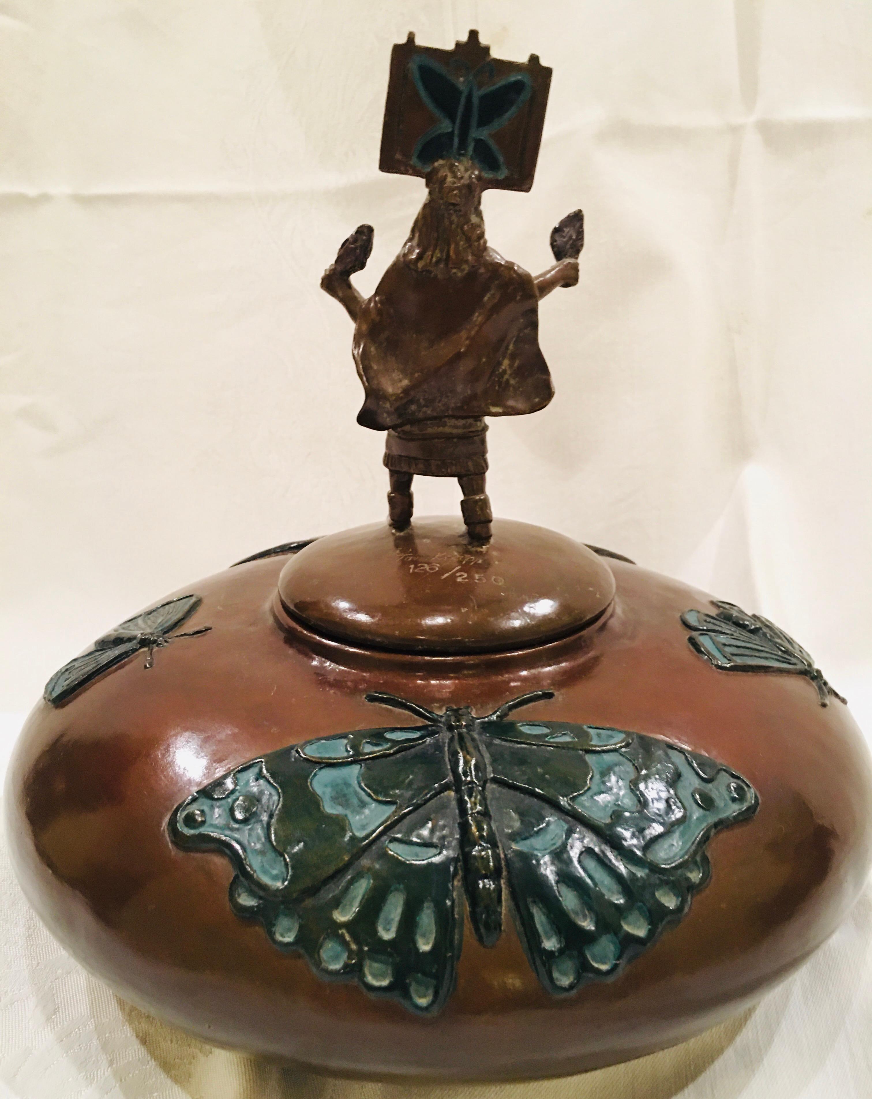 Tom Knapp’s low round “Butterfly Dance Pot” sculpture is actually a lidded box, the Zuni dancer performing the ritual dance astride the lid. 

Cast of dark brown oiled bronze, this sculpture features a Zuni woman performing the traditional dance