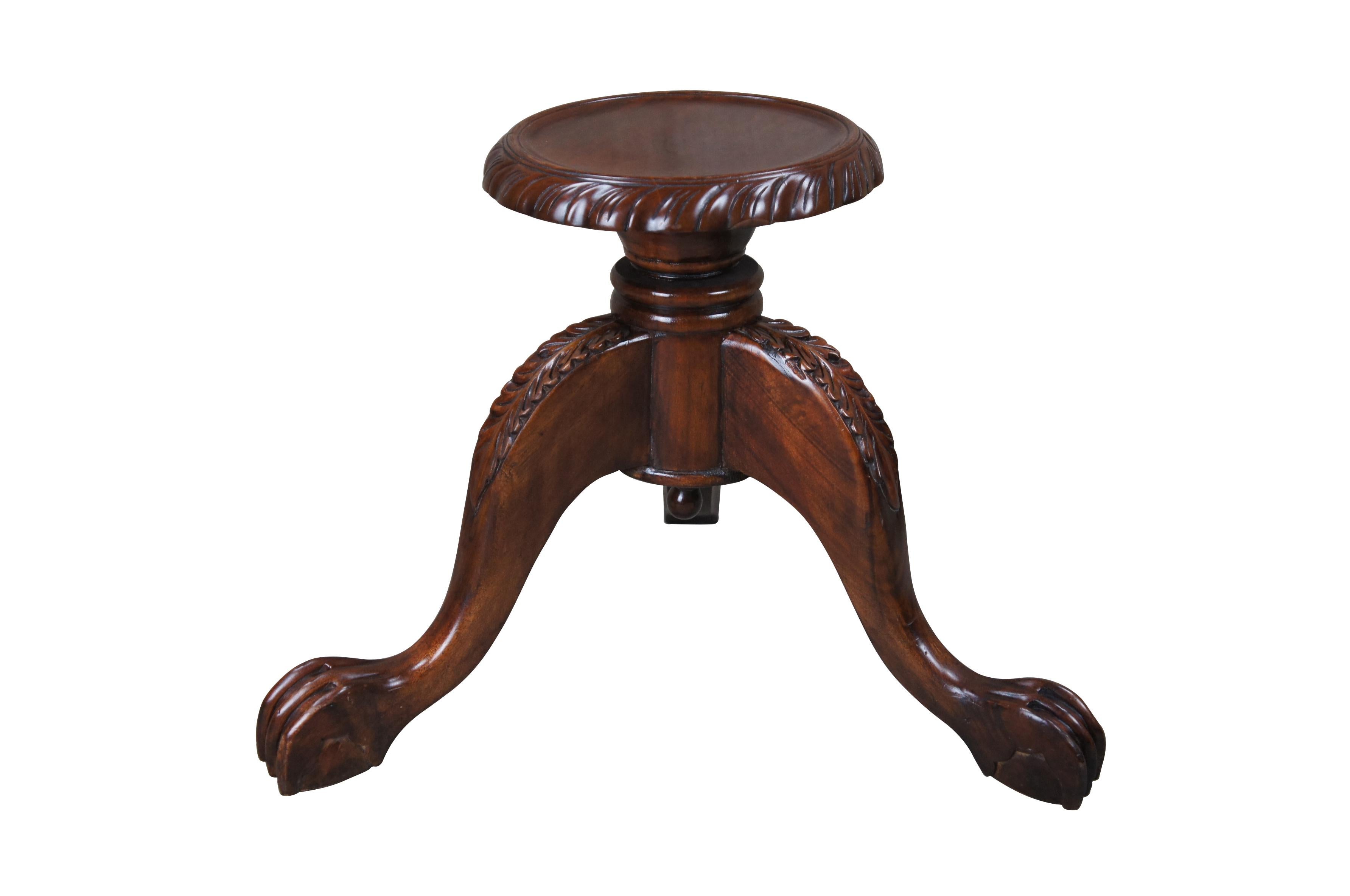 A beautiful 20th century carved mahogany low plant / candle stand or sculpture pedestal.  Features a circular top with gadrooning along the edge.  The top is supported by a bell shaped support with a ribbed base over three downswept cabriole legs. 