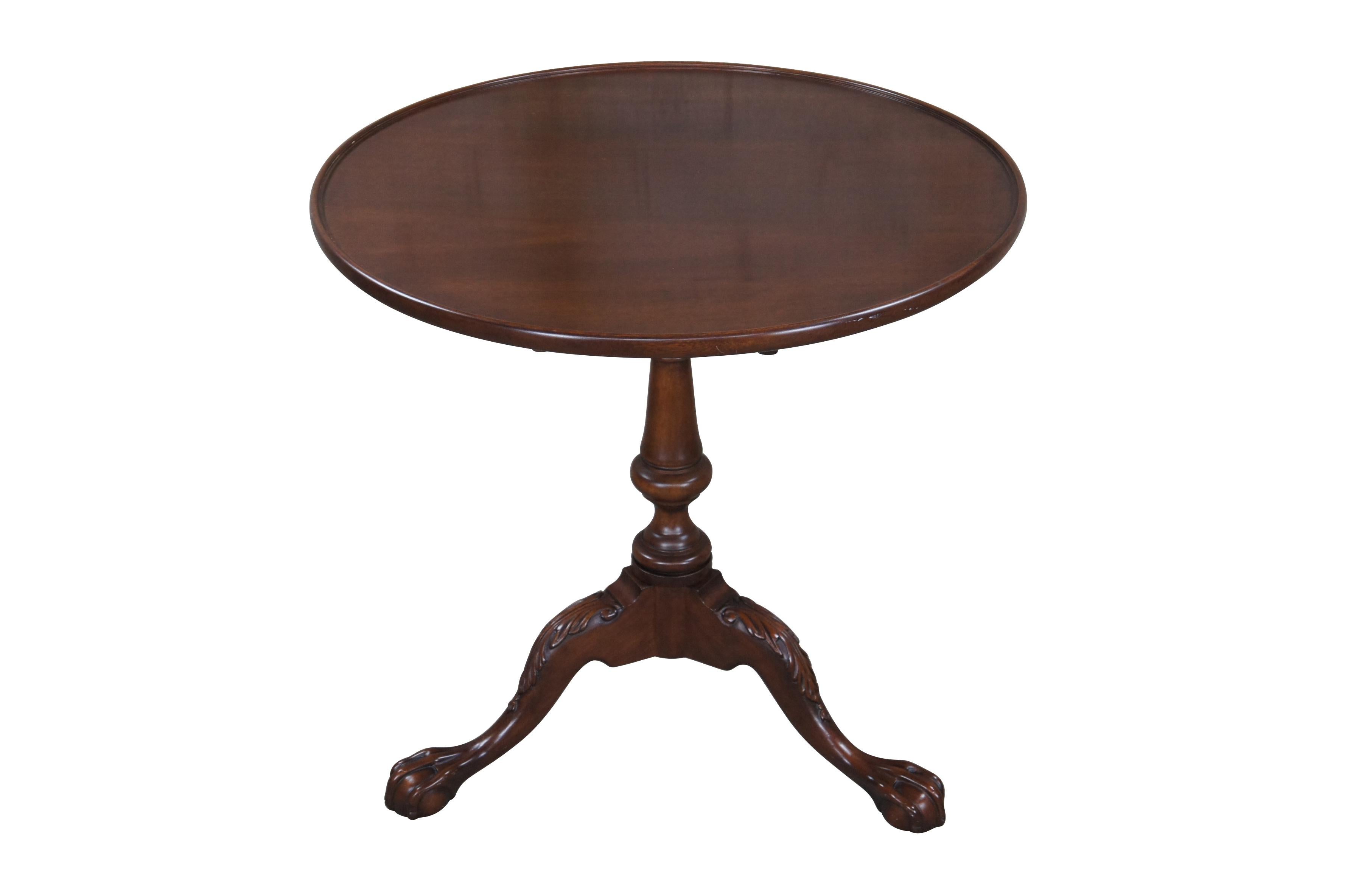 An impressive tea table drawing inspiration from Colonial and Chippendale styling, circa second half 20th century. Made from mahogany with a round tilt top over revolving birdcage and turned baluster base leading to downswept acanthus carved legs