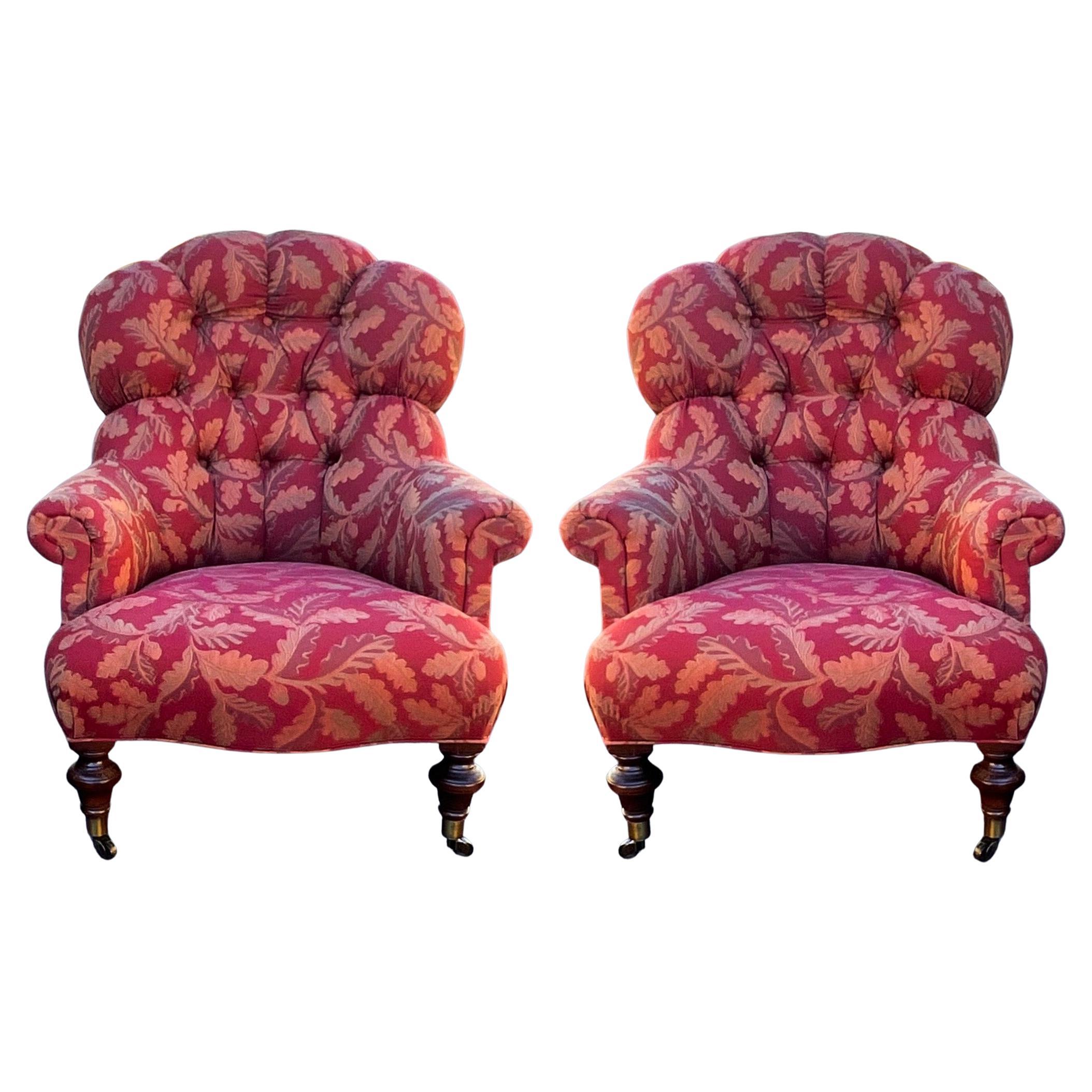 I love the form of these! This is a pair of English style tufted upholstered club chairs with turned mahogany feet on brass casters. The arm height is 22”. The leaf embroidered upholstery is vintage and shows lite wear.