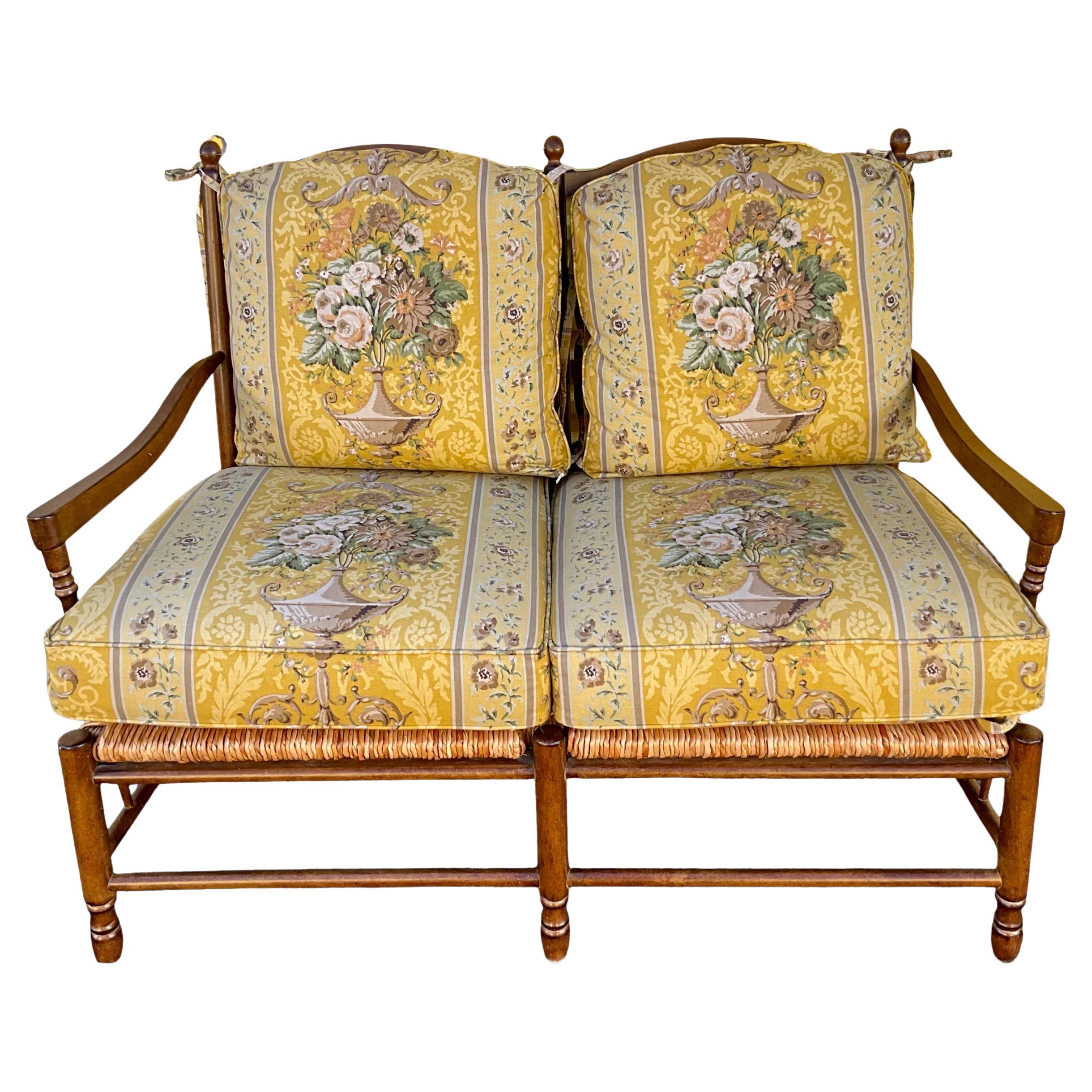 This is a late 20th century French country settee attributed to the manufacturer Pierre Deux. The frame appears to be maple with a sound rush seat. The neo-classical striped fabric is in very good condition. It has light wear and is unmarked. The