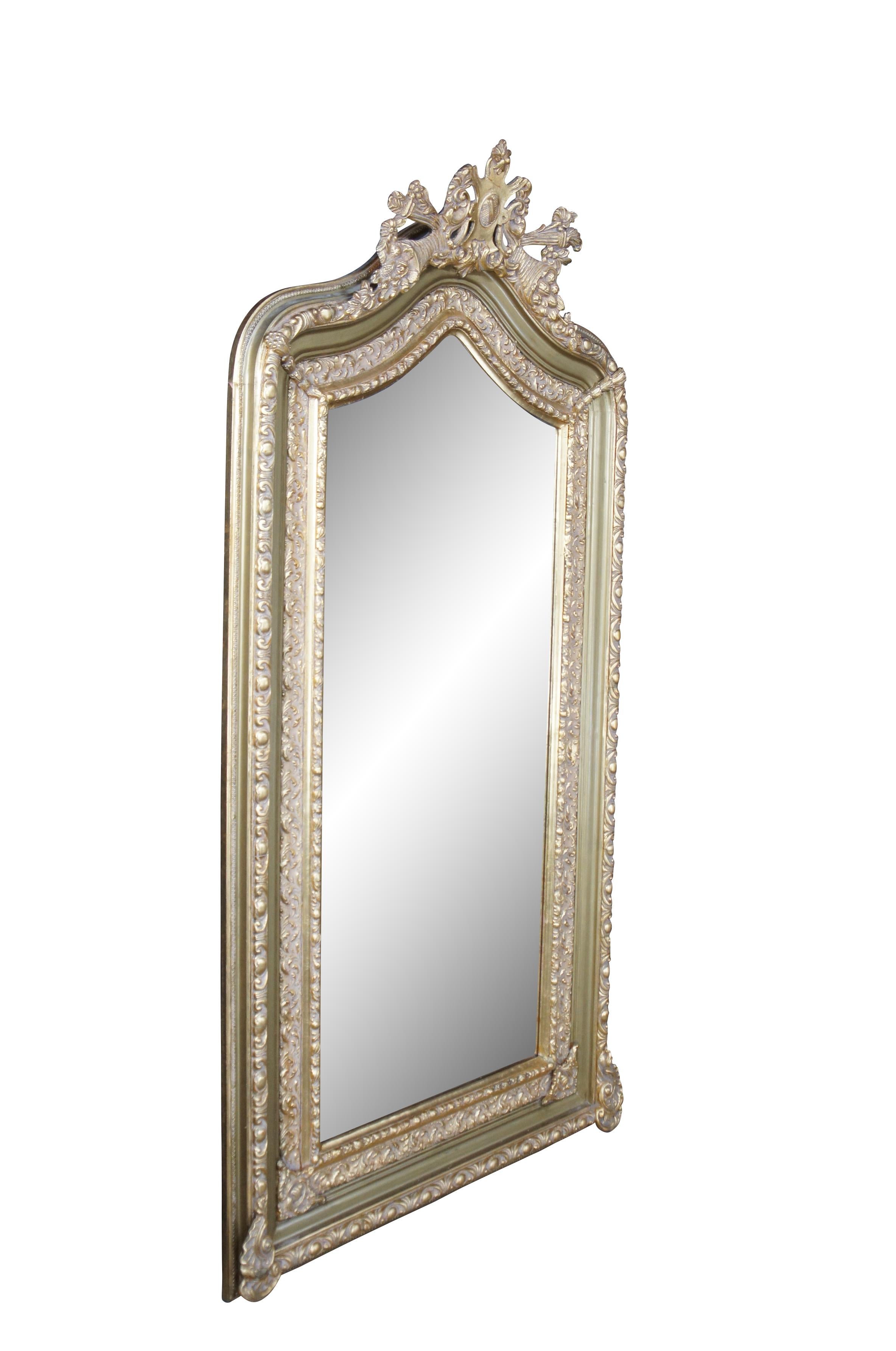 Un'eccezionale specchiera in stile barocco francese della fine del XX secolo.  Presenta una cornice in legno di pino dorato con un'alta corona arcuata e sagomata, centrata da un cartiglio unico con fogliame e cornucopia.  La cornice dello specchio