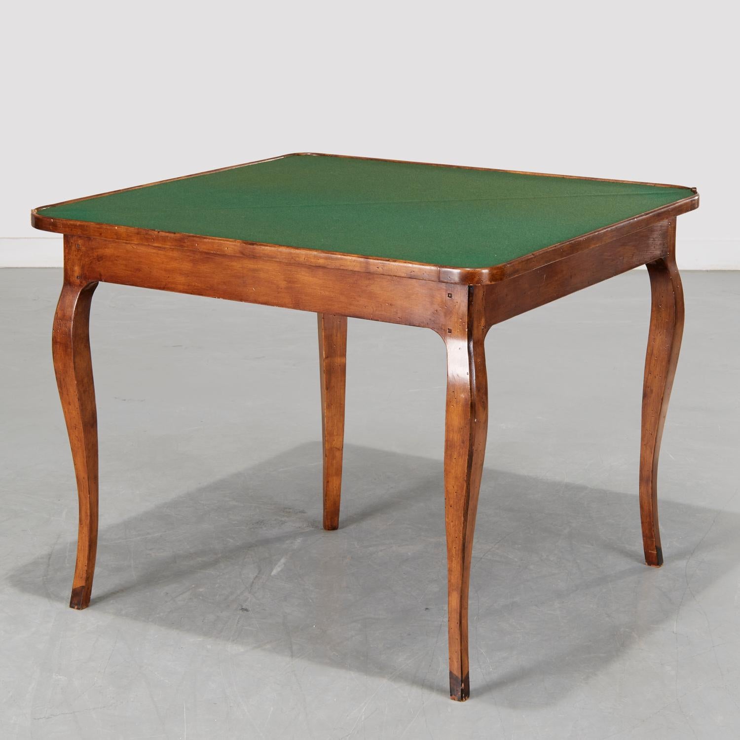 20th c., French Provincial Louis XV style triangular corner games table with a hinged top opening to a green baize gaming surface. The table folds out to a square on four curved corner legs. When folder. the middle rear leg becomes a  concealed