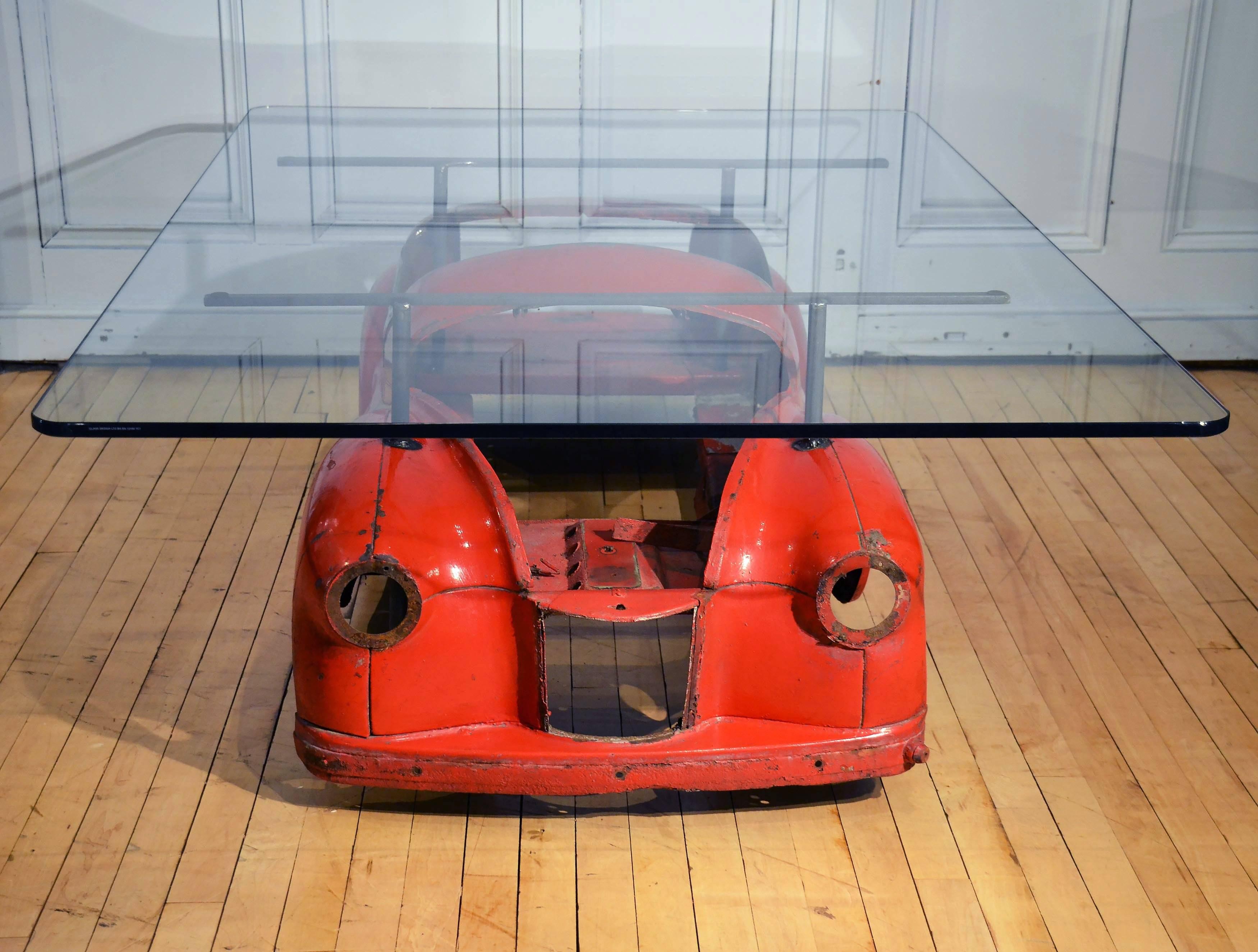 This fantastic industrial coffee table is individually designed and created with a distressed 1950s Red Austin J40 toy car mounted underneath a substantial glass top that measures 115 ml in thickness. The top is rectangular in shape with rounded