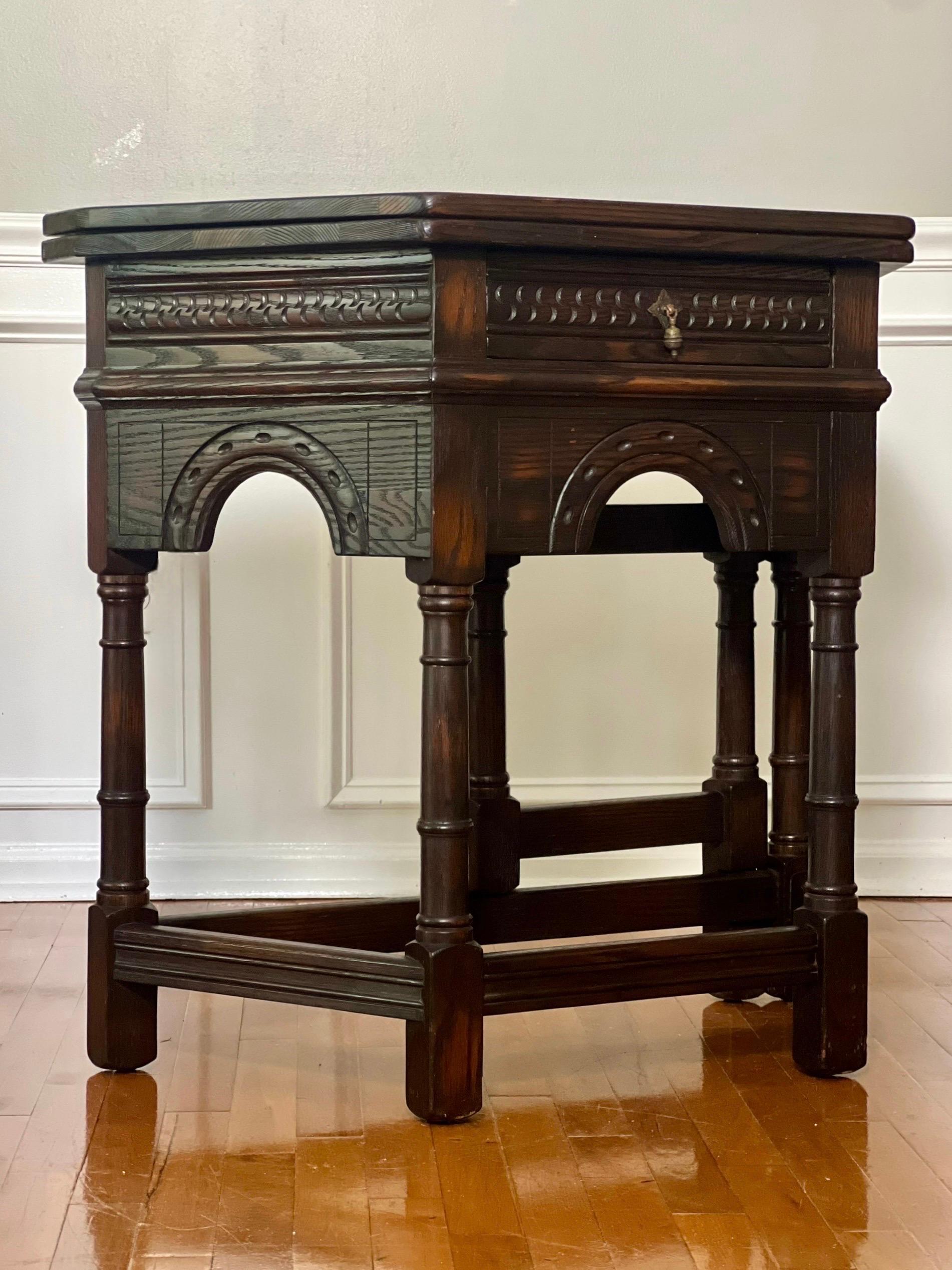 Jacobean style carved oak flip-top console or credence table by Peck & Hills, early 20th century. It features an arcaded frieze with geometrical carvings fitted with a single dovetailed drawer. The hinged top with strong hardware flips open to