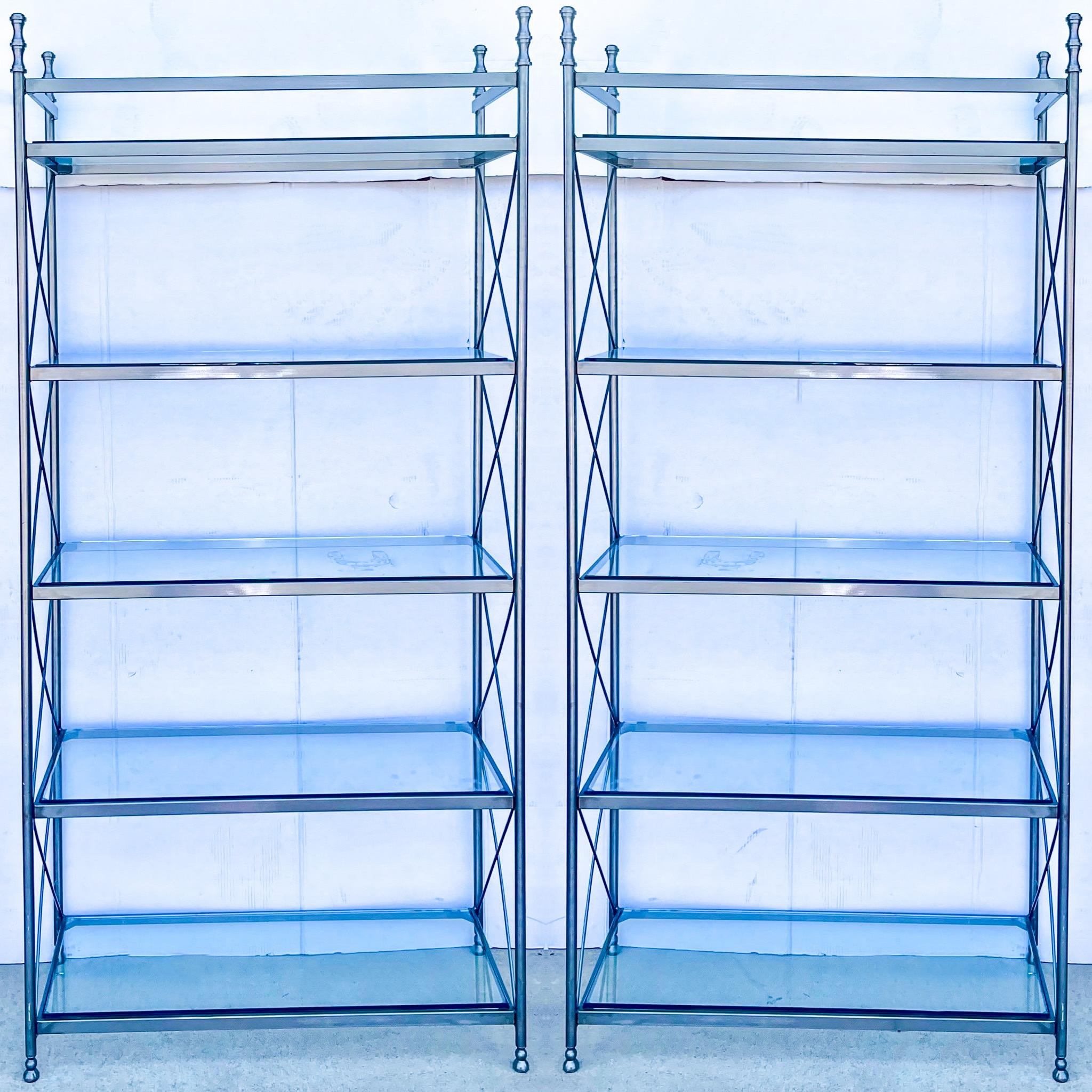 These make a strong statement! This is a pair of brushed steel etageres in the manner of Maison Jansen. They have removable glass shelves. The x-frame lends a clean elegance to the set. From the floor to the first shelf is 4.5”, to the second is