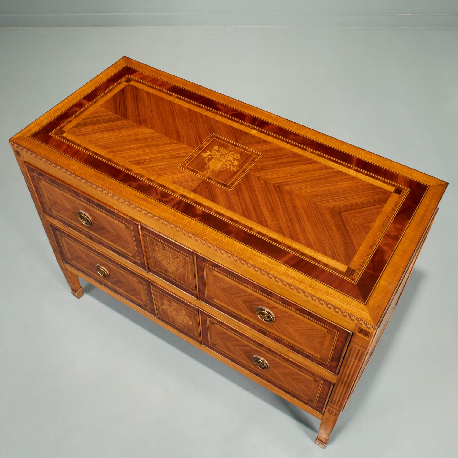 20th c., commode by Maitland-Smith, the two-drawer chest with brass ring pulls, raised on square tapering legs, maker's metal tag to inner drawer. The fine marquetry and parquetry on this piece is extensive and varied; 5 panels depicting an urn with