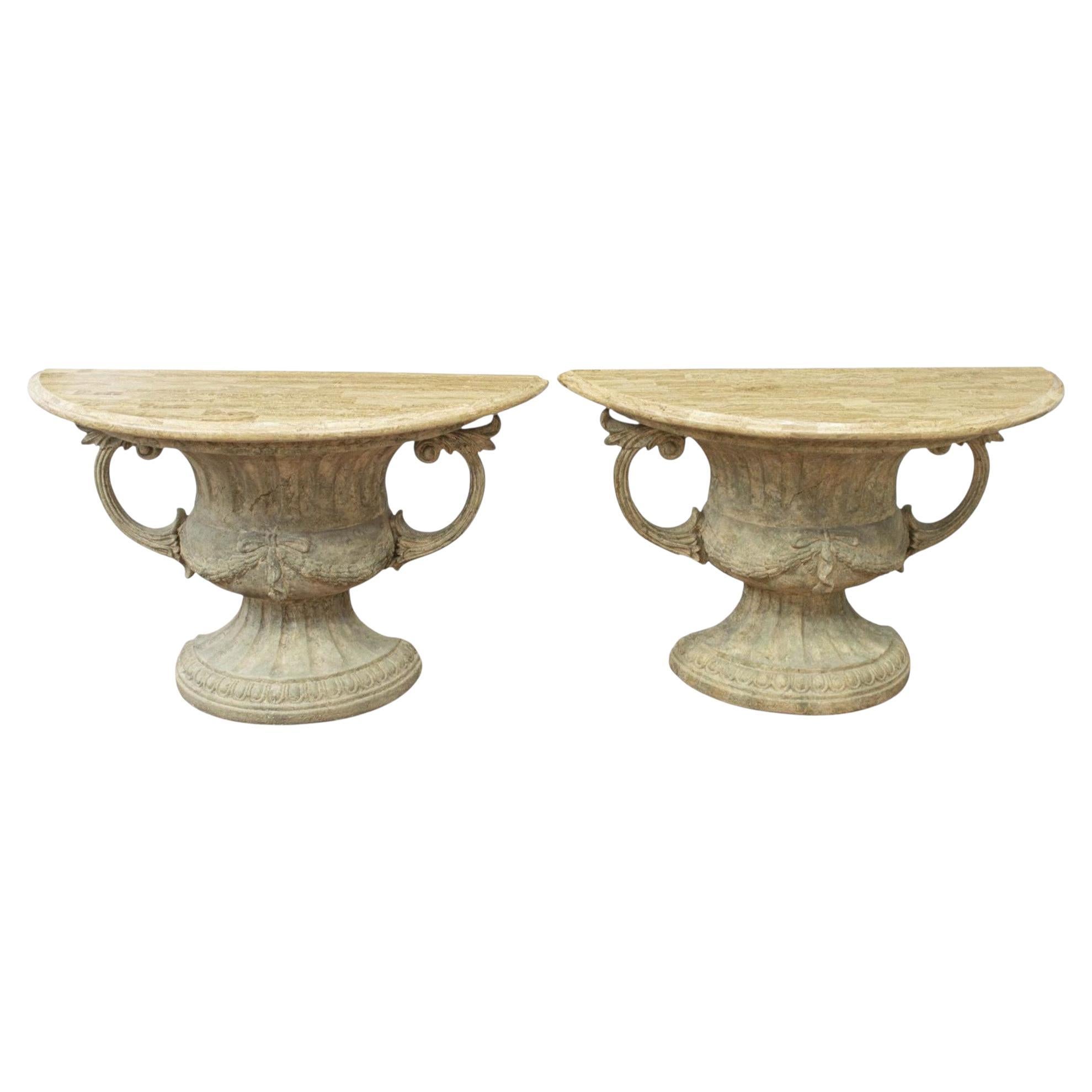 This is a pair of neoclassical style urn form console tables with attached tessellated marble tops. They have intentional distressing. The body is cast fiberglass. They are unmarked and in very good condition.