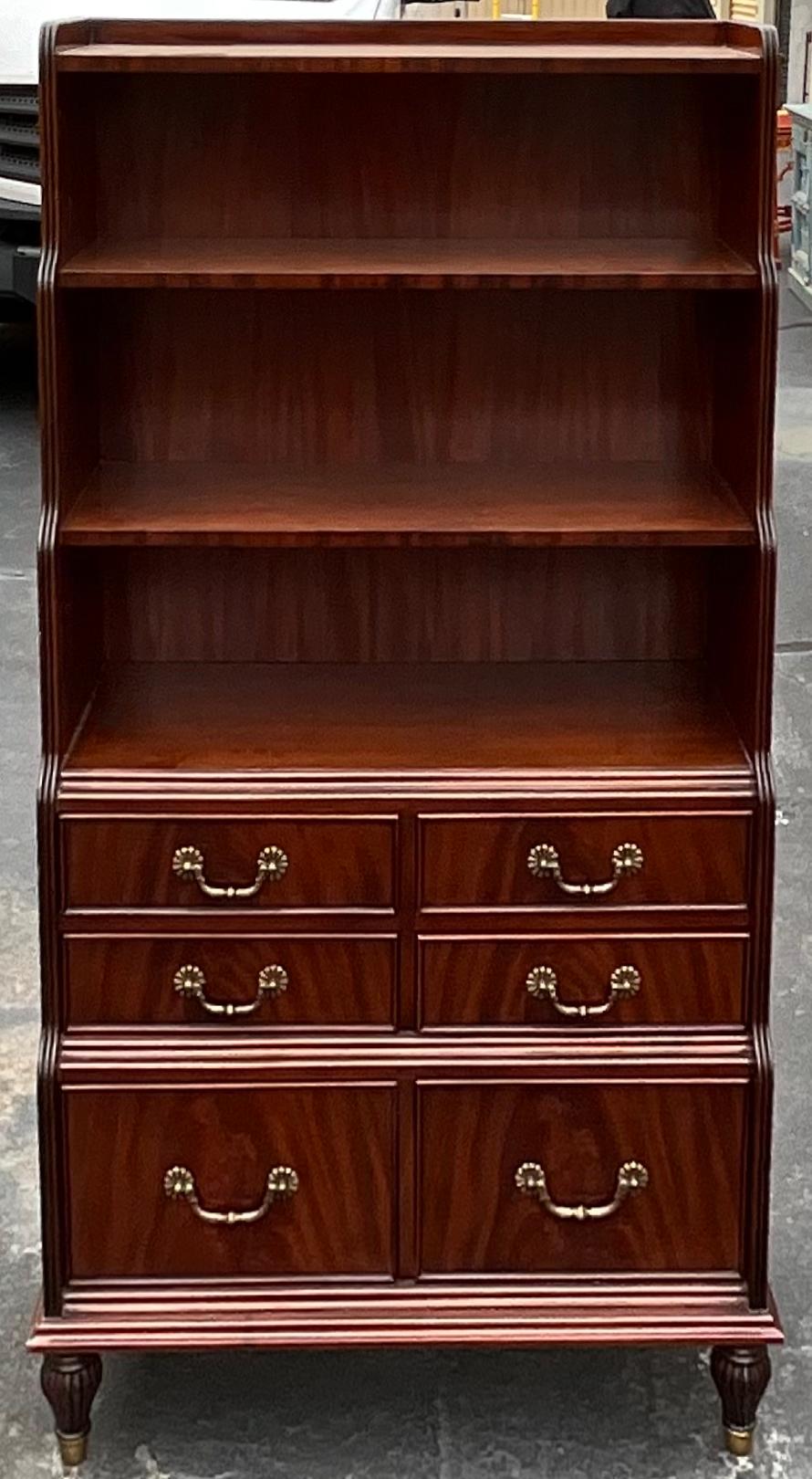 This is a pair of Regency style flame mahogany bookcases with brass hardware. They are a wonderful versatile size. The pair have dovetail construction with regard to the drawers, and turned feet. They are unmarked. 


