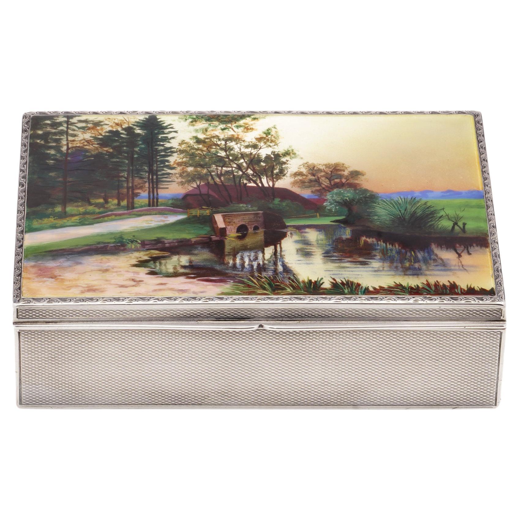 Antique early 20th Century sterling silver cigarette box with enamelled cover, featuring a landscape scenery.
The complete box showcases a traditional engine-turned design on each of its four sides as well as the base.

Made in America, Circa 1900's