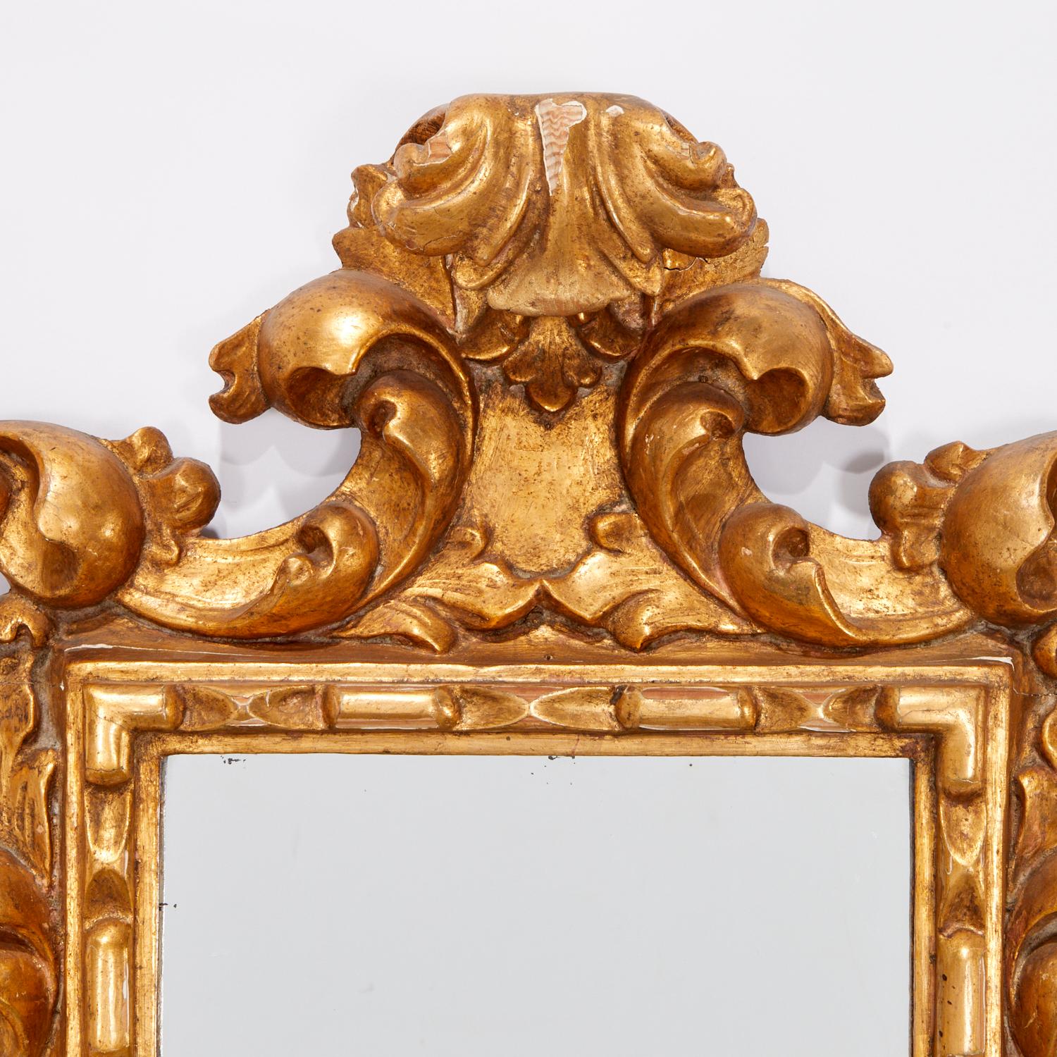 First half of the 20th c., Spain, a Baroque style giltwood mirror. The openwork foliate scroll frame, topped with acanthus crest, is surrounding rectangular mirror glass. There is an old paper label on back. 

This mirror would be a stunner in a