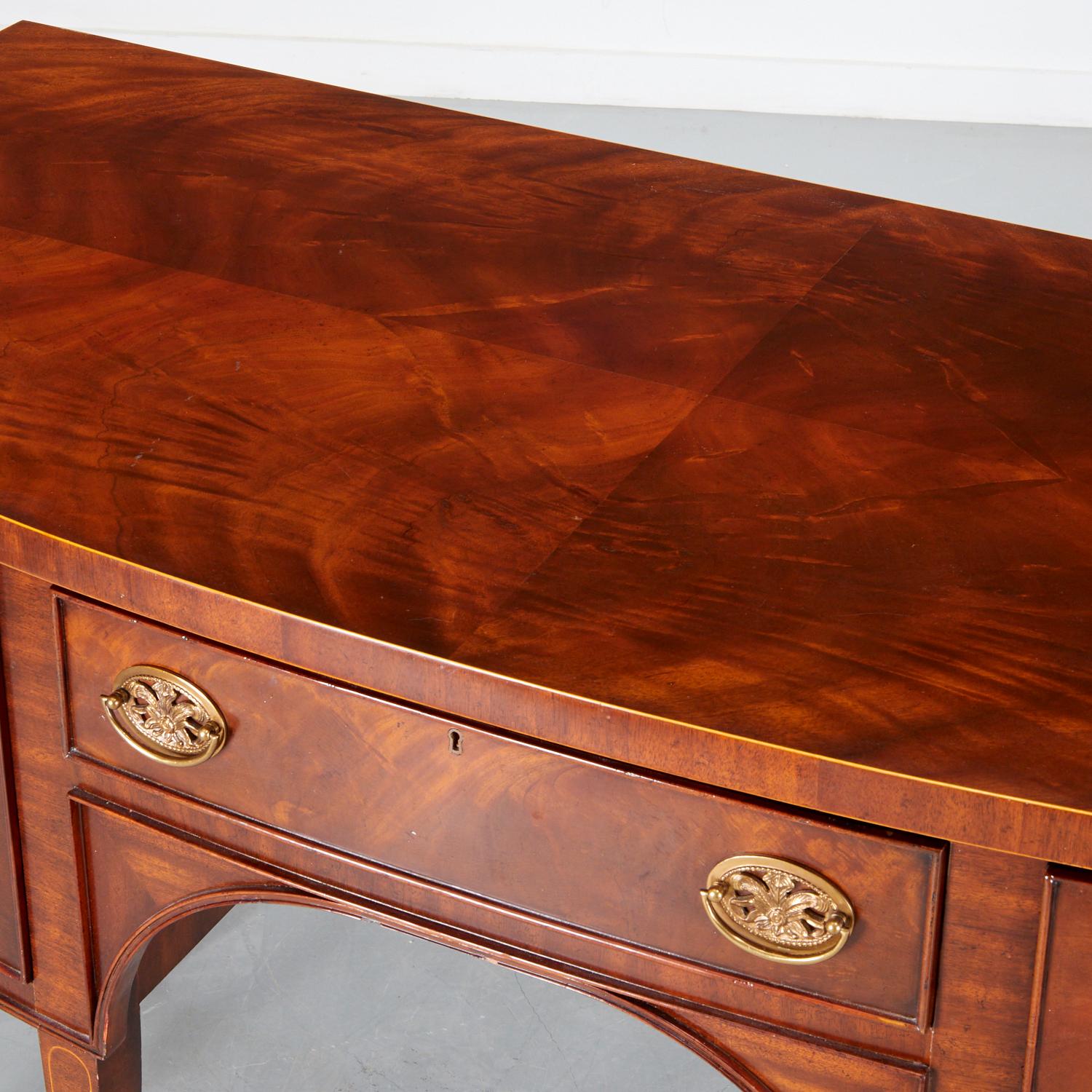 20th c., Georgian style mahogany sideboard with inlaid stringing and brass hardware raised on marlborough legs.

This is a lovely sideboard with a bookmatched flame mahogany veneer top and delicate brass hardware. The beadwork on the drawer fronts