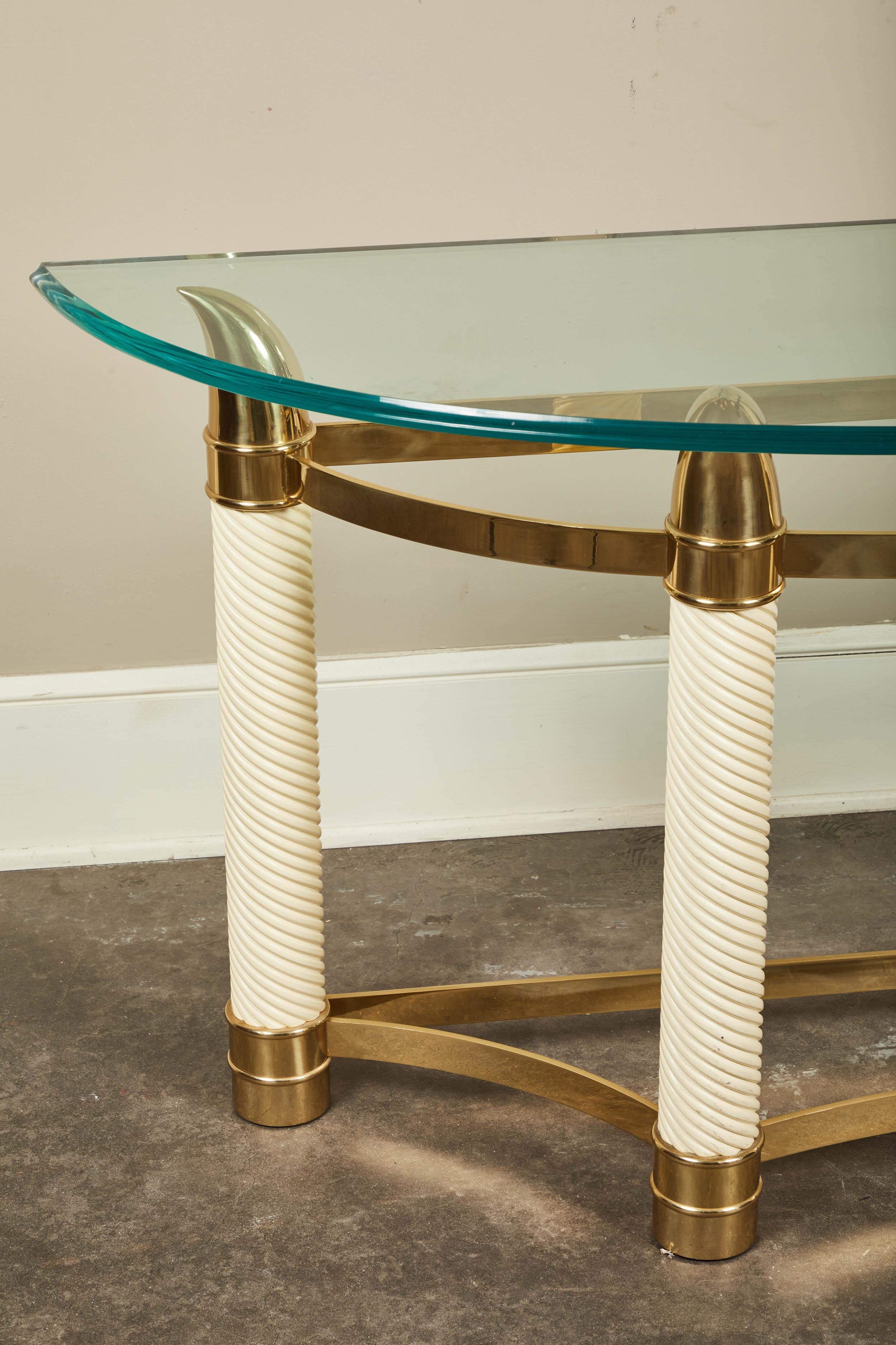 A Tommaso Barbi style faux tusk demilune console. Off-white columns with brass detailing on either end. Glass top gently floats on the spear ends of the faux tusk legs.