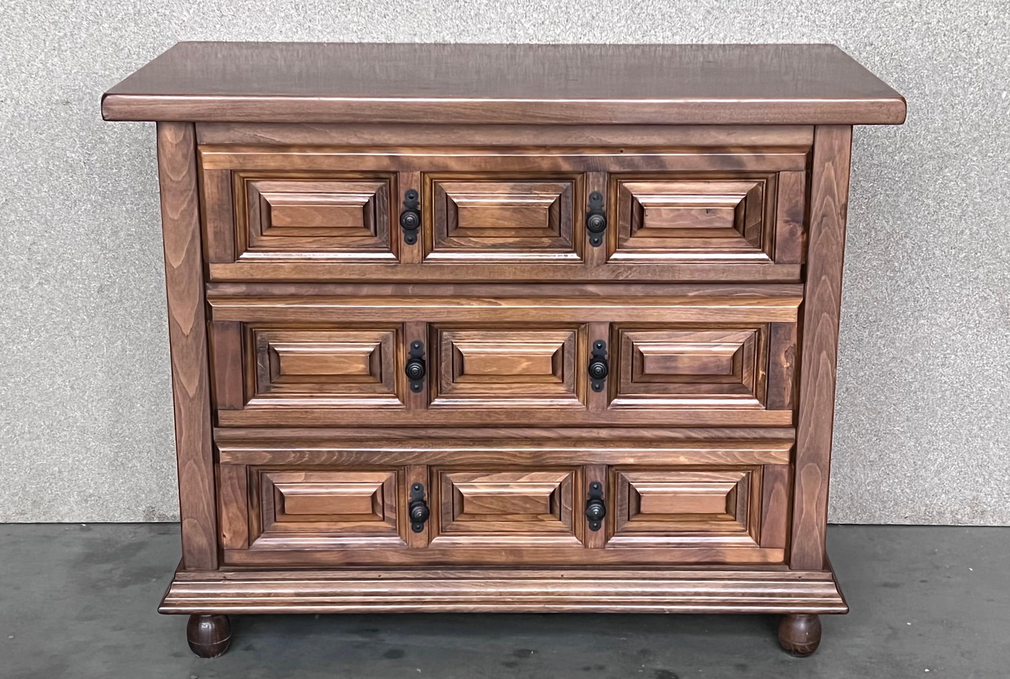 From Northern Spain, constructed of solid walnut, the rectangular top with molded edge atop a conforming case housing three drawers paneled with solid walnut, raised on four round legs.
Carved on the molding sides of the front and original iron