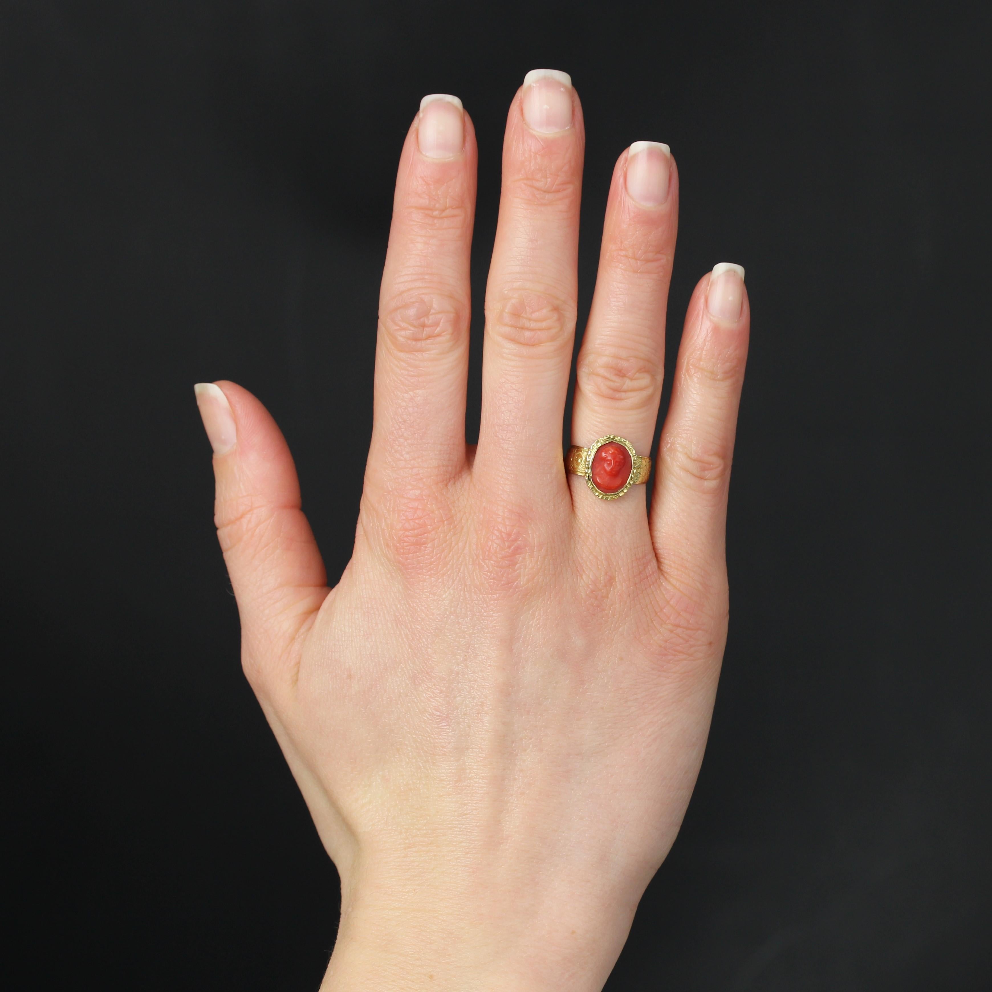 Ring in 18 karat yellow gold.
A charming antique ring in yellow gold, its band is engraved with floral motifs on either side of the opening and the head is adorned with a cameo on coral representing a child's face. Small chasing details surround the