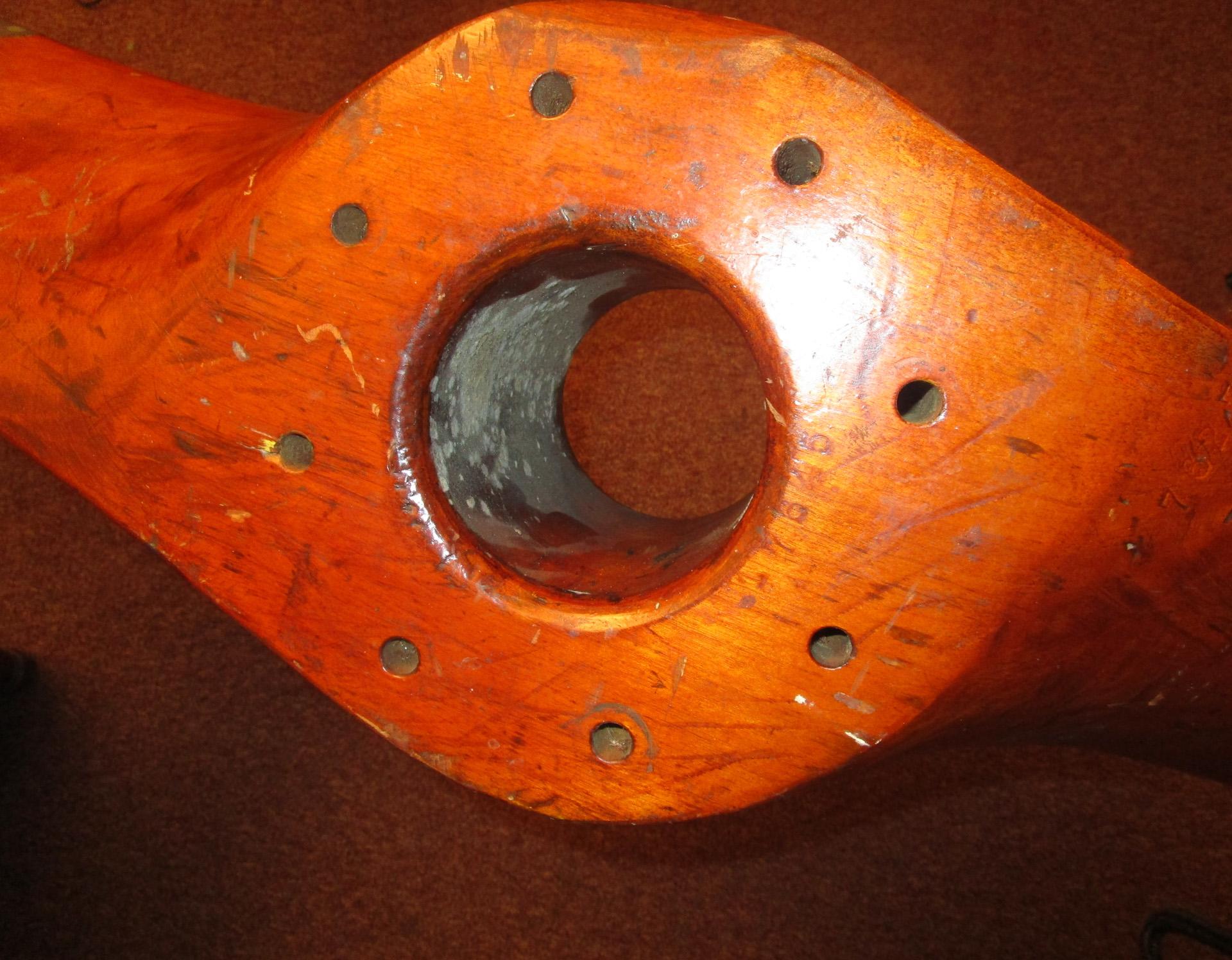 This English 20th century very large mahogany airplane propeller features folded brass blade guards with copper rivets and bears the original manufacturer’s proof marks. They are hard to distinguish, but it seems to read:
 FAH21?
?76271
No.17645