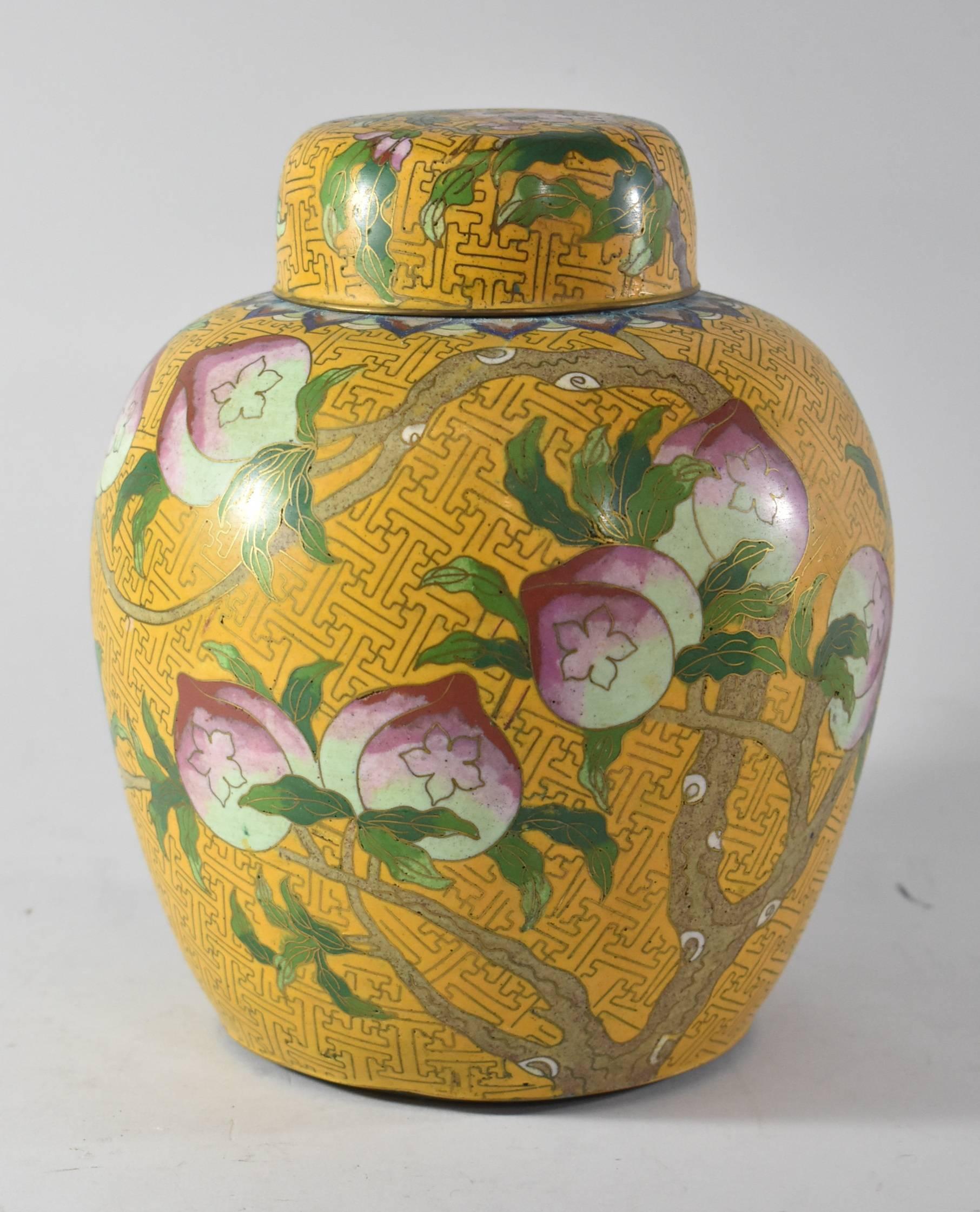 A beautiful pair of large cloisonne ginger jars with lids. These are done in the Peach tree Pattern. Background is yellow; tree branches with peaches are depicted along with some brightly colored flying bats. The interior of the jars and tops are