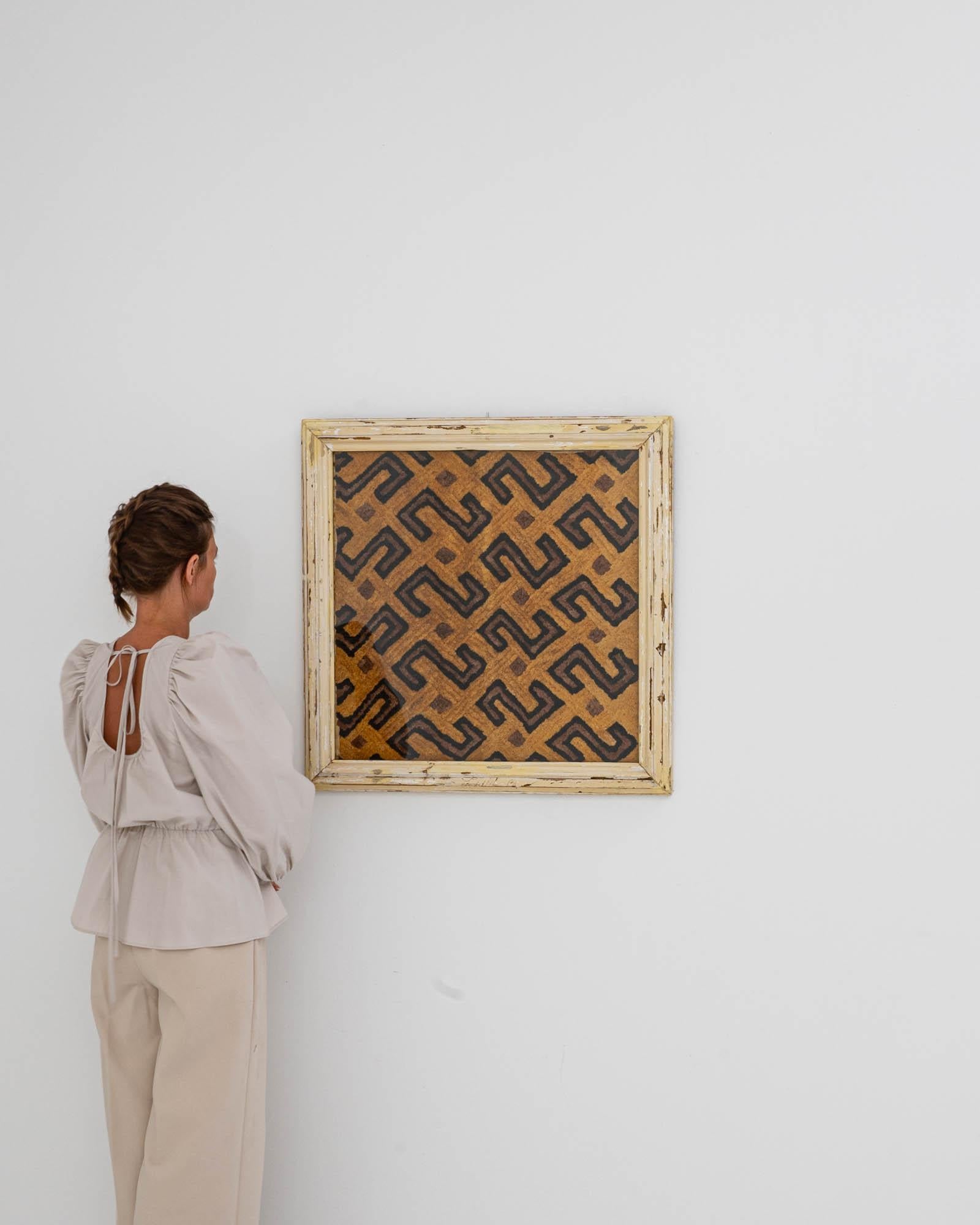 This 20th Century African Artwork, encased in a wooden frame, is an exquisite piece of cultural history. The geometric pattern, reminiscent of traditional African motifs, creates an engaging visual effect that draws the eye and holds attention. The