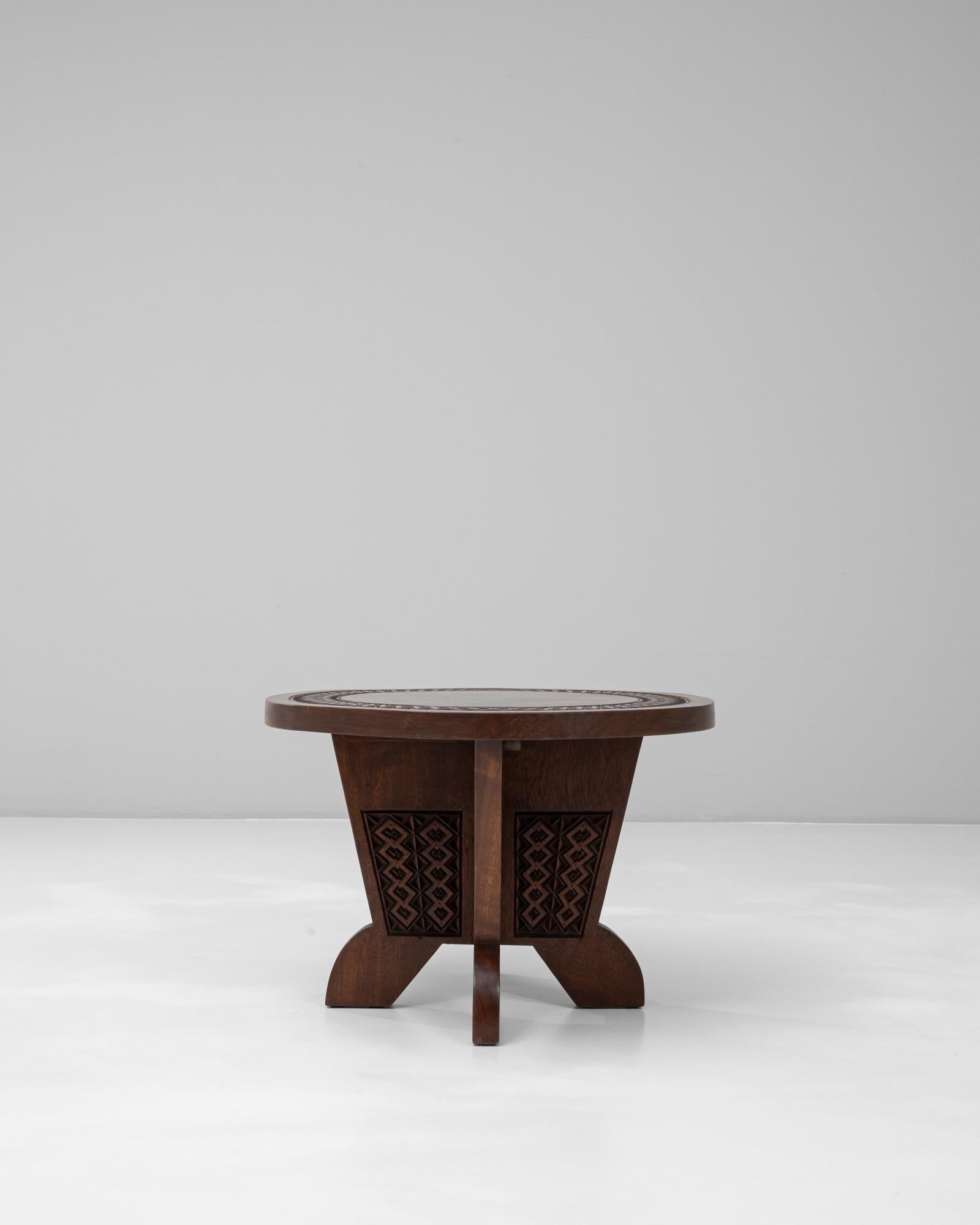 Cette table basse en bois africain sculpté du 20e siècle témoigne d'un savoir-faire exceptionnel et d'une esthétique richement détaillée ancrée dans le design traditionnel. Le plateau circulaire présente une bordure géométrique complexe sculptée à