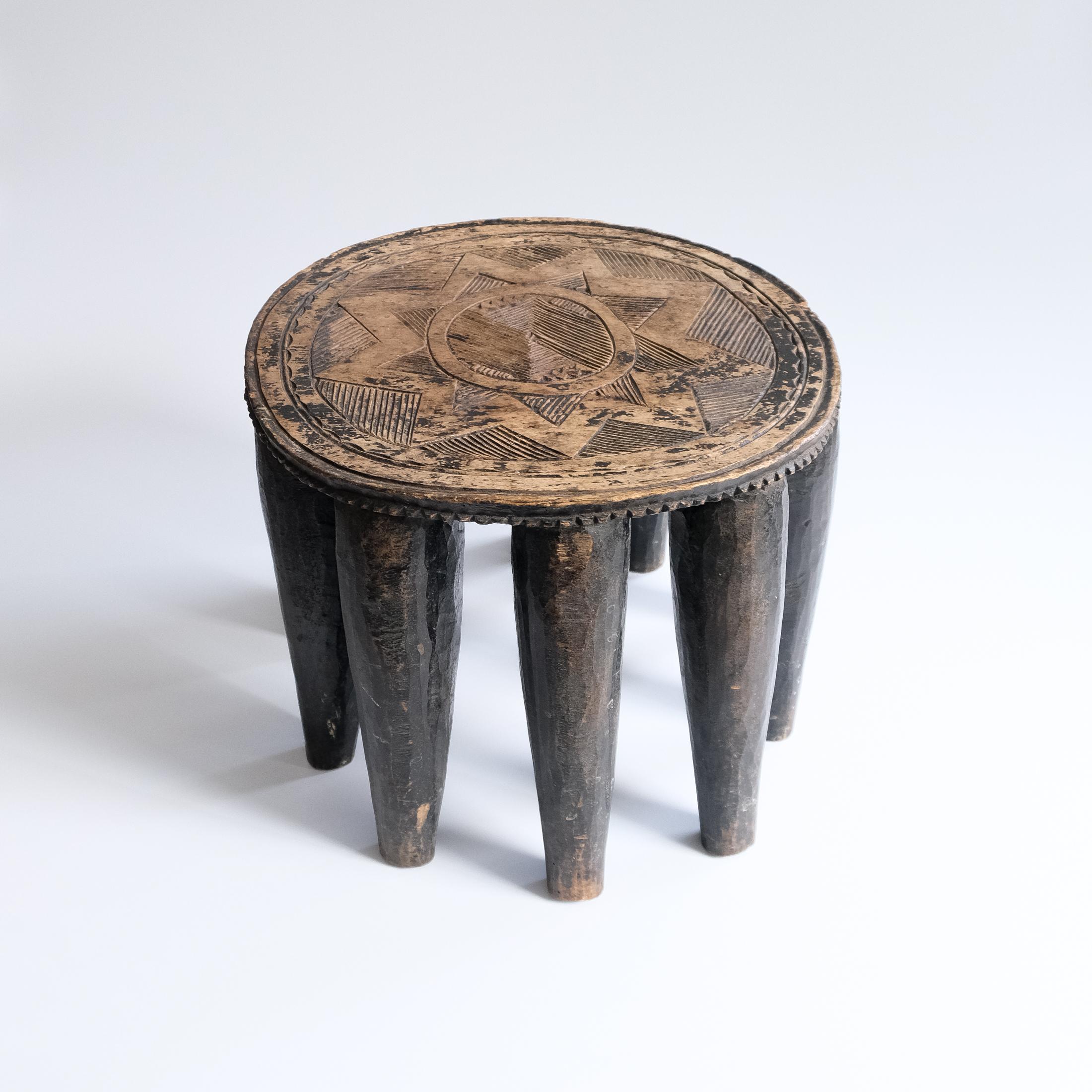 Nous proposons à la vente un magnifique tabouret ou table à dix pieds africain vintage du 20e siècle, sculpté à la main, provenant de la tribu Nupe du Nigéria, en Afrique, et datant des années 1950 environ.

Ce tabouret tribal circulaire