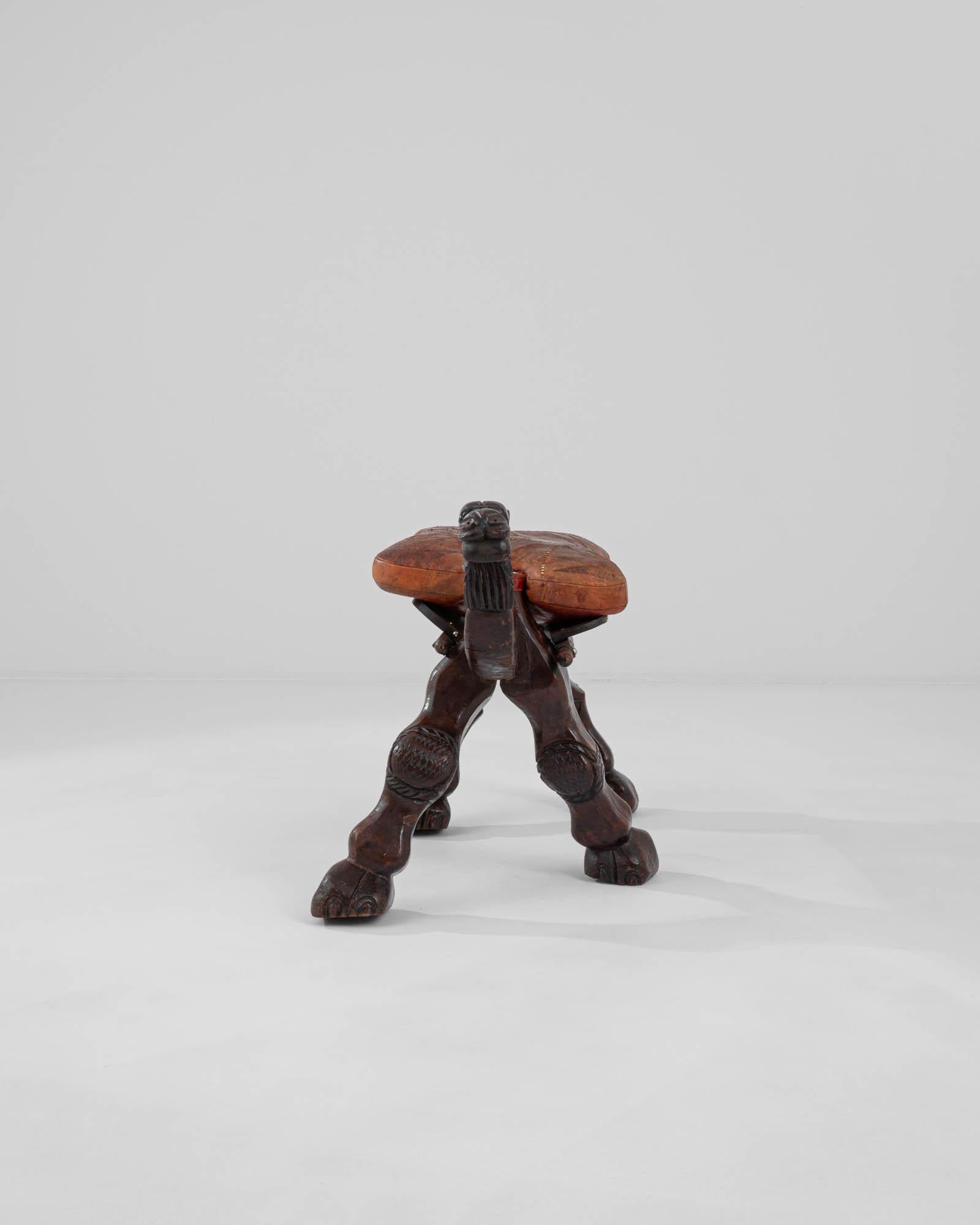 Beautifully carved into the shape of a camel, this wooden stool makes a truly unique vintage accent. Hand-crafted in Africa in the 20th century, the camel is depicted in motion, one foot ahead of the other in a hoofed stride. The comfortable leather