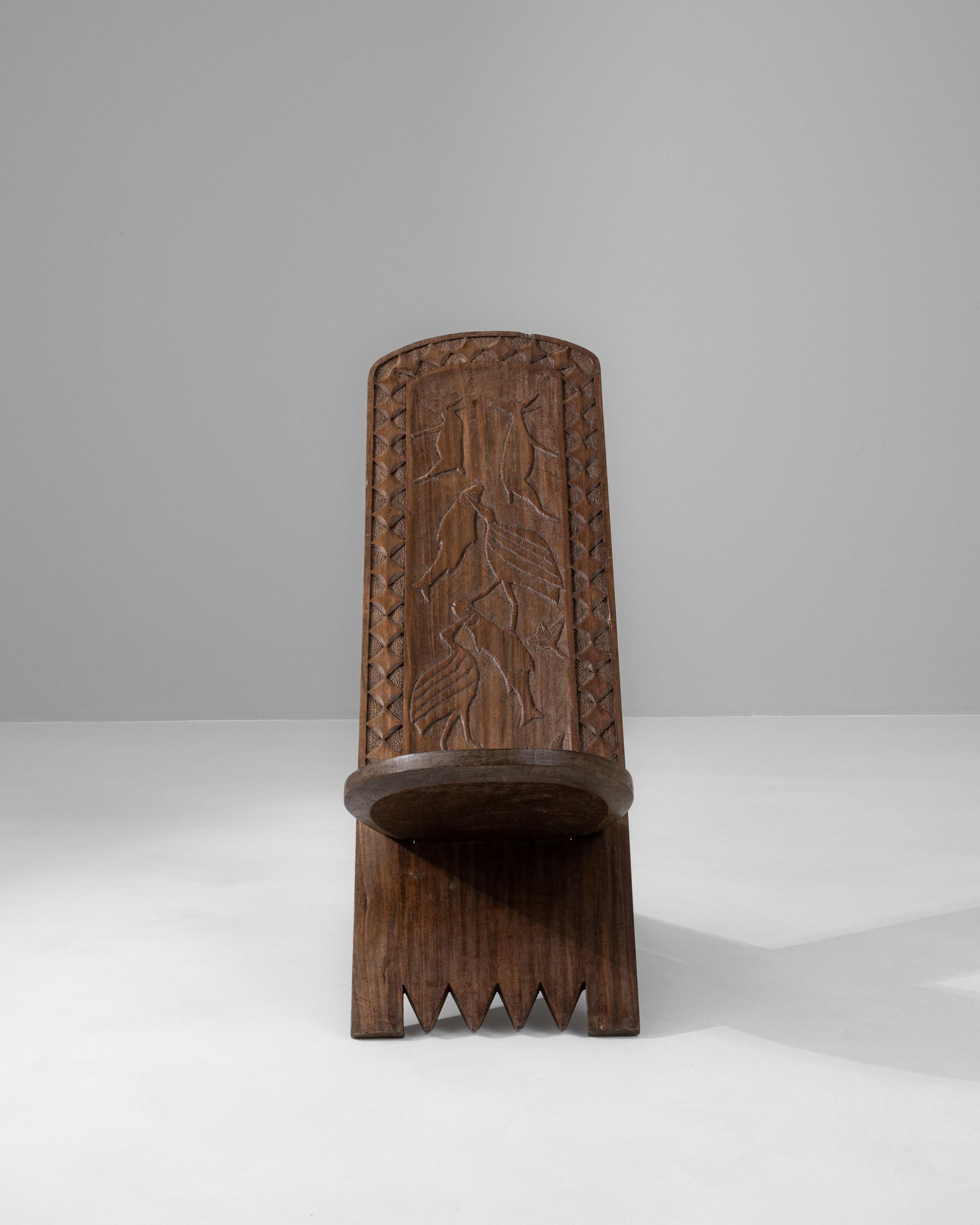 Unveil the essence of African artistry with this early 20th-century wooden chair, a piece that marries functionality with cultural expression. Crafted with the utmost care by skilled artisans, this chair's robust form is hewn from a dark, solid