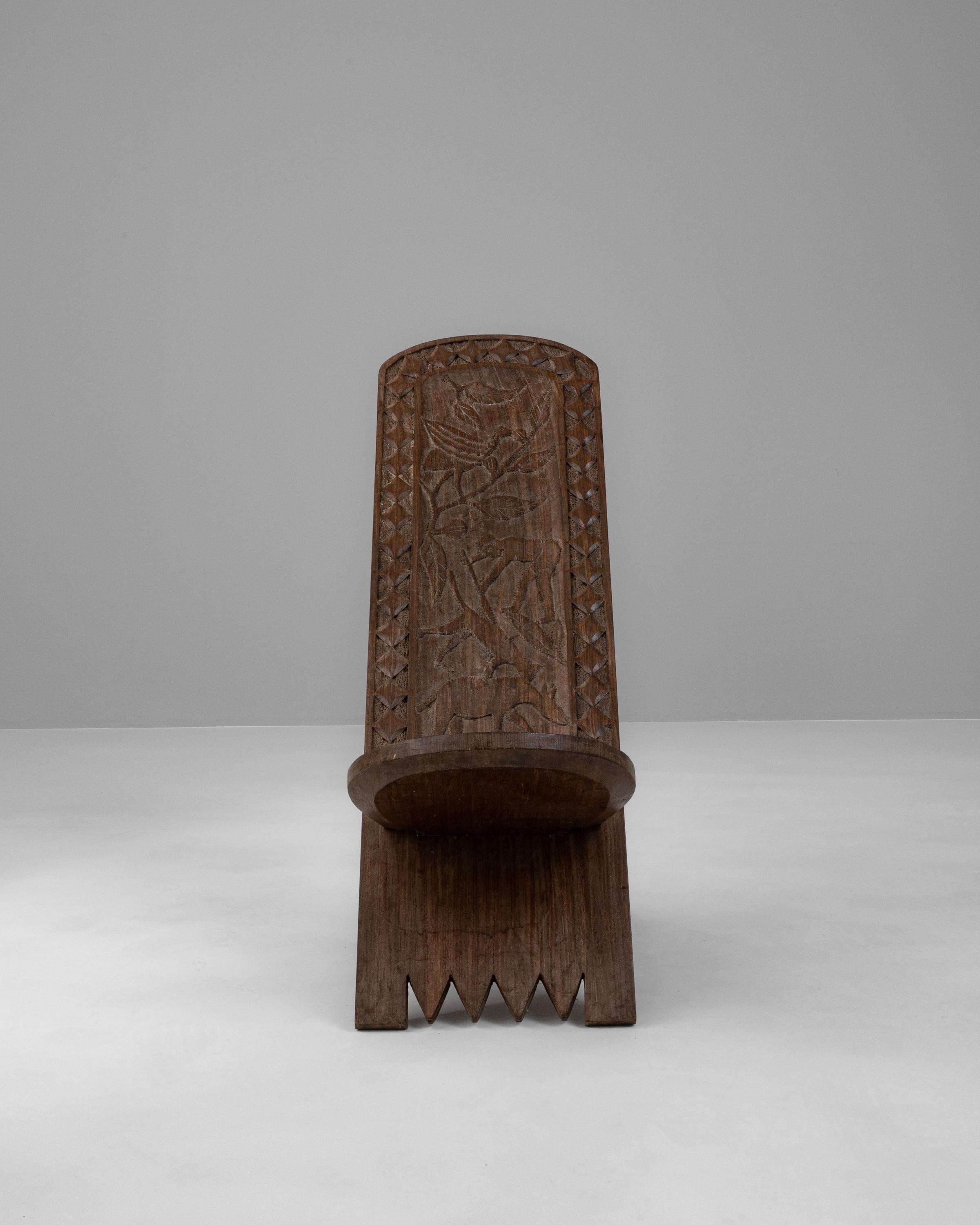 Unveil the essence of African artistry with this early 20th-century wooden chair, a piece that marries functionality with cultural expression. Crafted with the utmost care by skilled artisans, this chair's robust form is hewn from a dark, solid