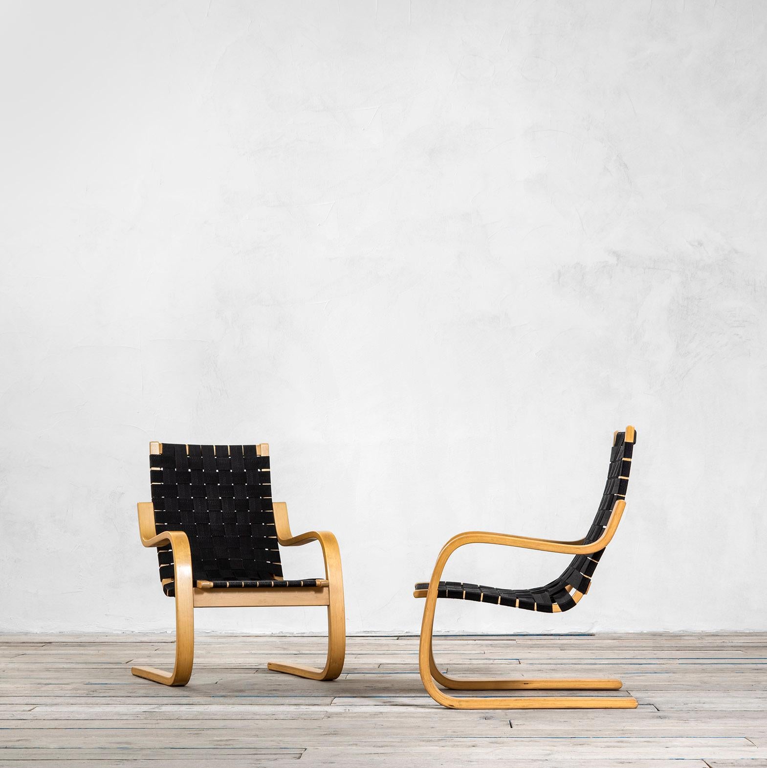 Couple of armchairs designed by Alvar Aalto model n. 406 for Artek. The structure is in curved birch wood and the seating is in strips of black fabric. 
Published in: C & P. Fiell, 1000 Chairs, p. 281, Taschen, 2006, pag. 165.
Good condition,