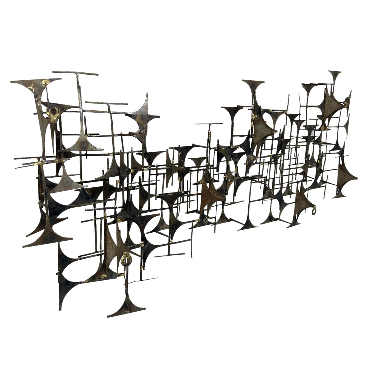 A black-grey, vintage Mid-Century Modern American abstract Brutalist wall sculpture made of handcrafted gilded metal, designed by Marc Weinstein in good condition. The detailed large wall décor piece is enhanced by small metal pieces. Wear