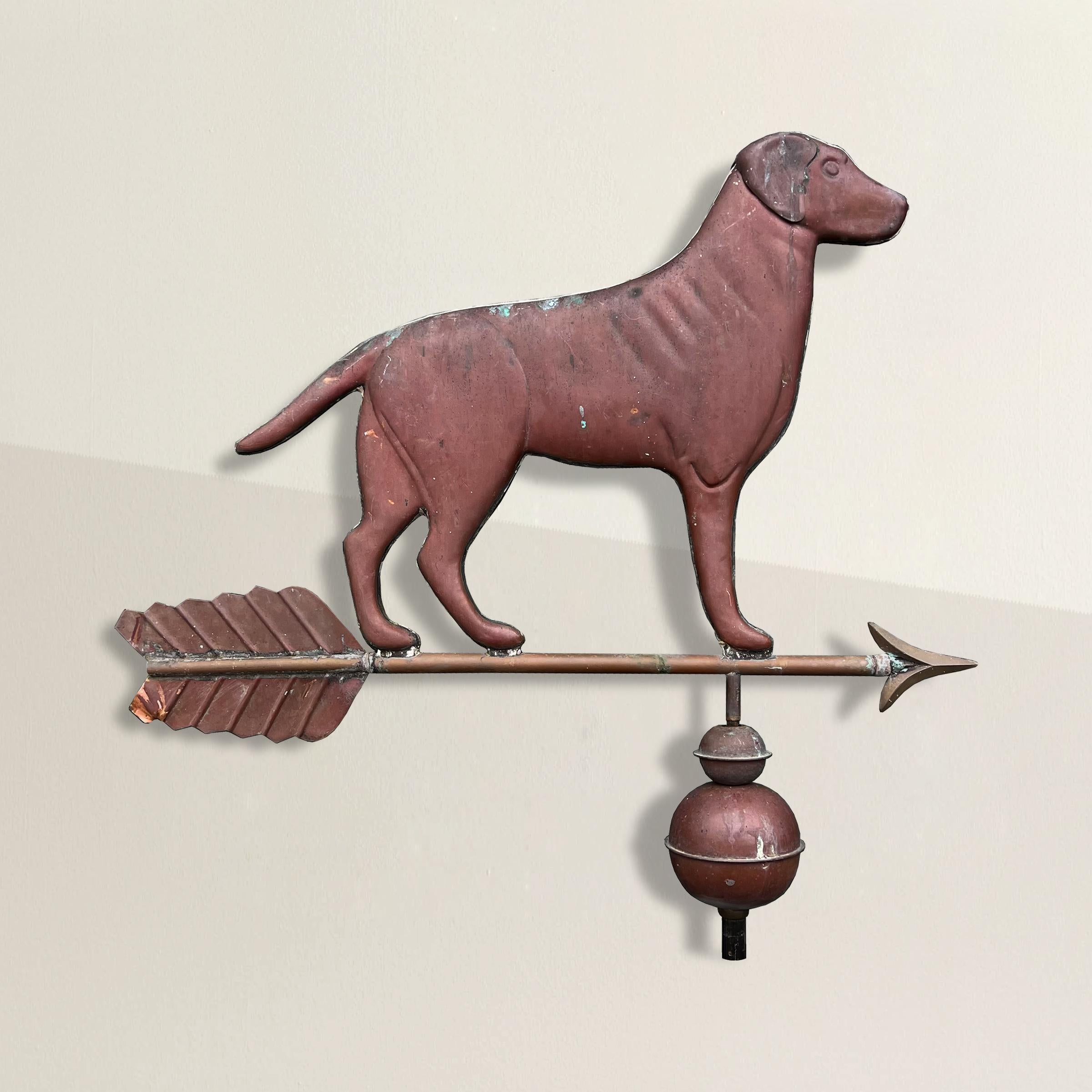 This 20th-century American copper Labrador weathervane is a captivating blend of artistry and functionality. Crafted with meticulous detail, it features a majestic Labrador standing proudly atop an arrow and two hollow spheres. The copper patina