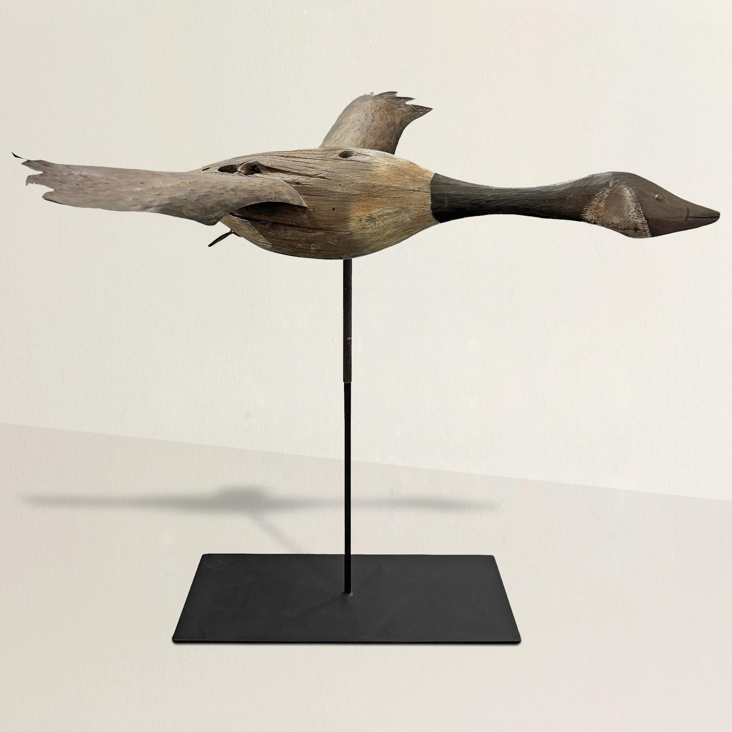 This 20th-century American Folk Art masterpiece is a life-size Canada goose that captures the essence of rural creativity and cultural heritage. Its outstretched wings, crafted from snipped tin, exhibit a sense of dynamic motion, while the body,