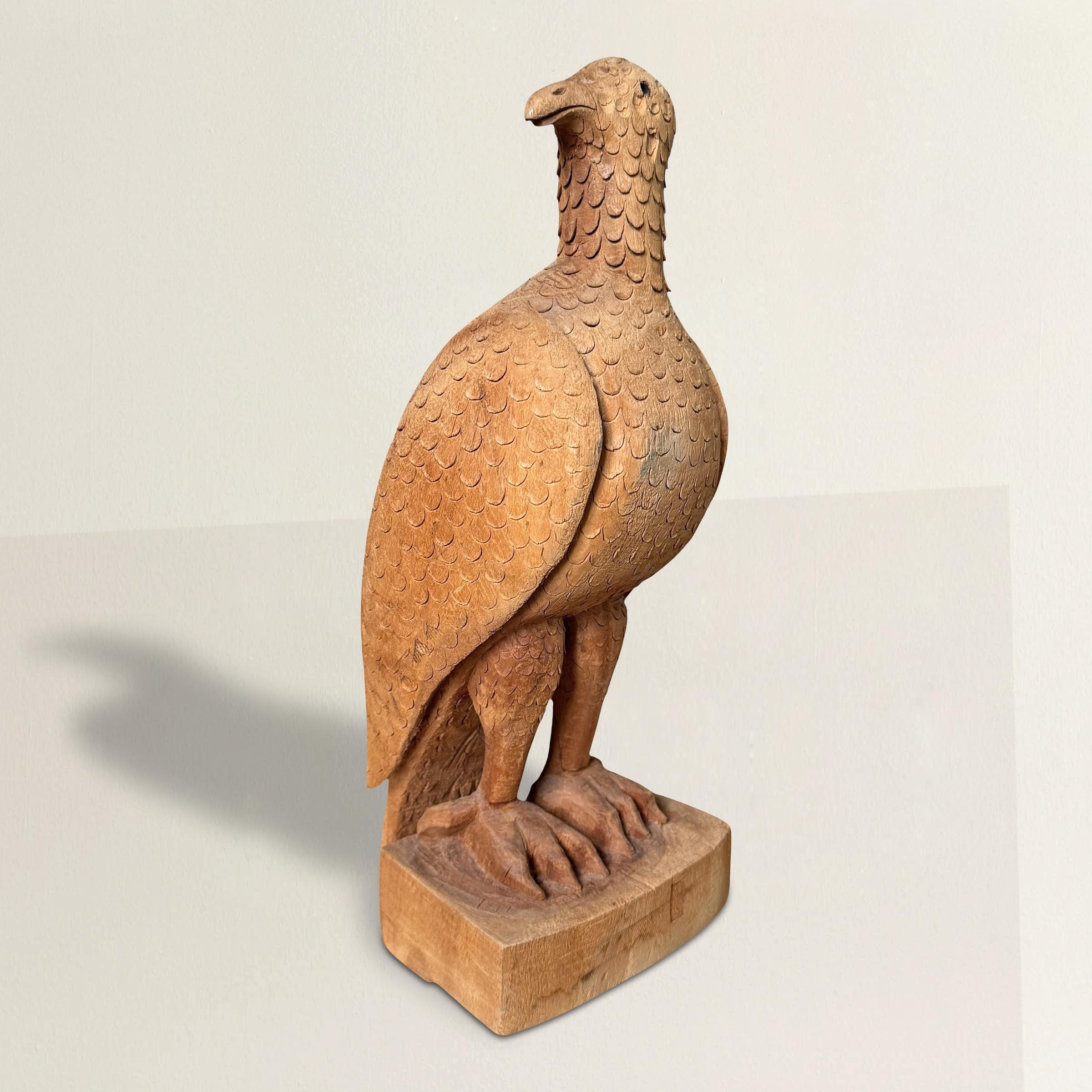 Cet aigle en bois sculpté à la main de l'art populaire américain du XXe siècle capture l'esprit de l'art naïf avec une authenticité frappante. Perchée avec assurance sur un bloc simple, la forme de l'aigle est rendue avec une charmante